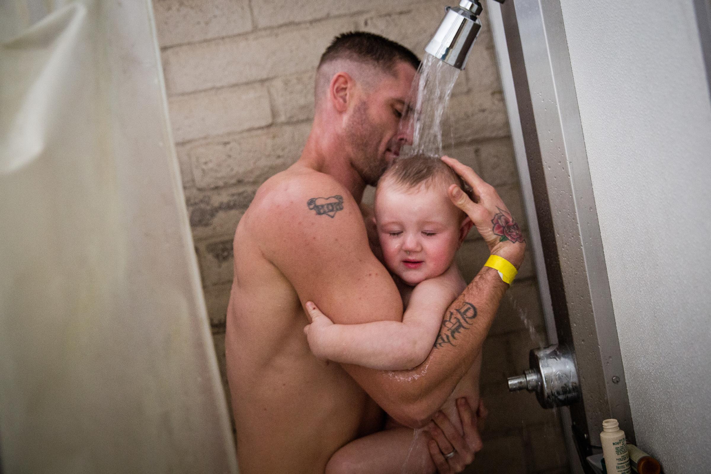 Albert Morrison, Sr., and his 14-month-old son Albert, Jr. take a shower for the first time in three days at the evacuation center at the Butte County Fairgrounds in Chico, California on Feb. 15, 2017.