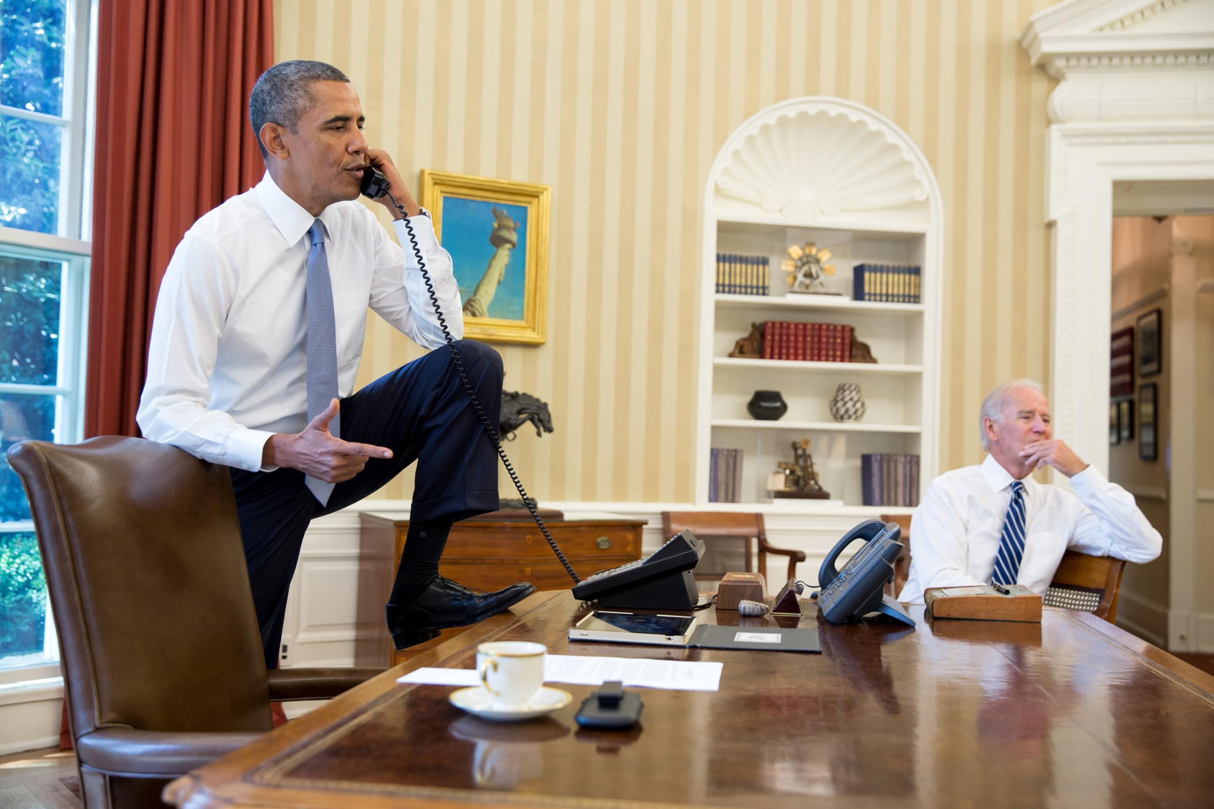 U.S. President Barack Obama (L) talks on the phone with Speaker of the House Boehner as Vice President Joe Biden listens in the Oval Office of the White House August 31, 2013 in Washington, DC.