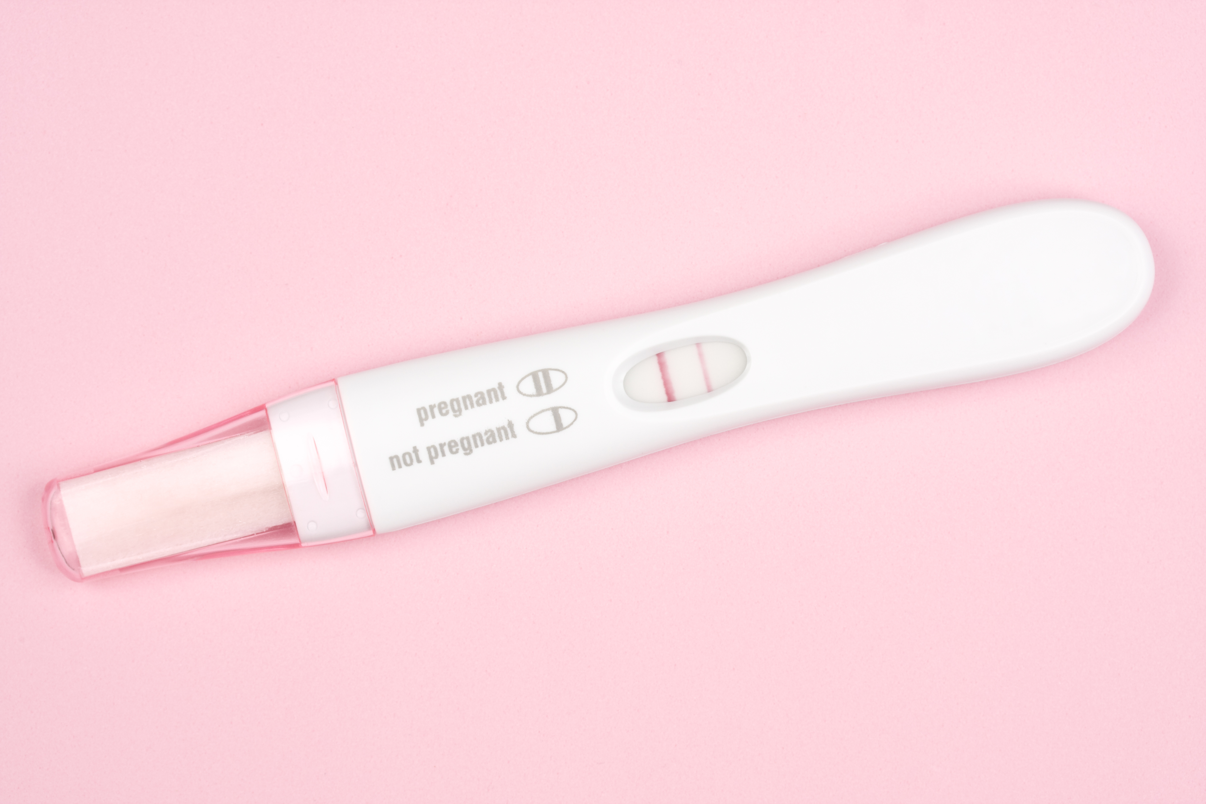 Positive pregnancy test on pink background (cillay—Getty Images/iStockphoto)