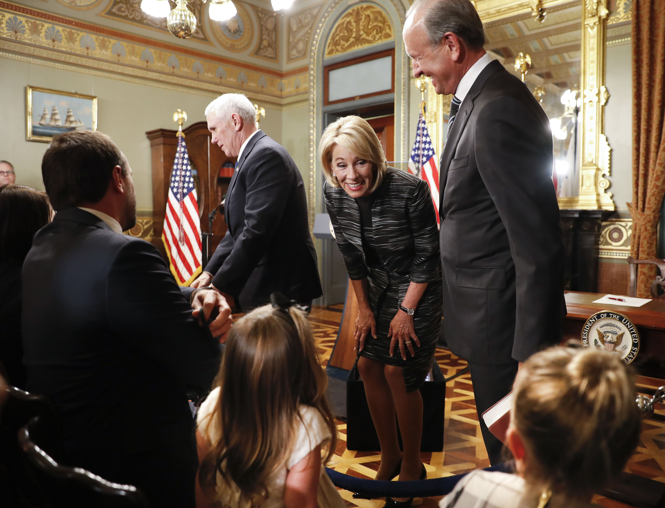 Education Secretary Betsy DeVos, center, leans down to greet children and other guests following her swearing in ceremony administered by Vice President Mike Pence, left, in the Eisenhower Executive Office Building in the White House, on Feb. 7, 2017.