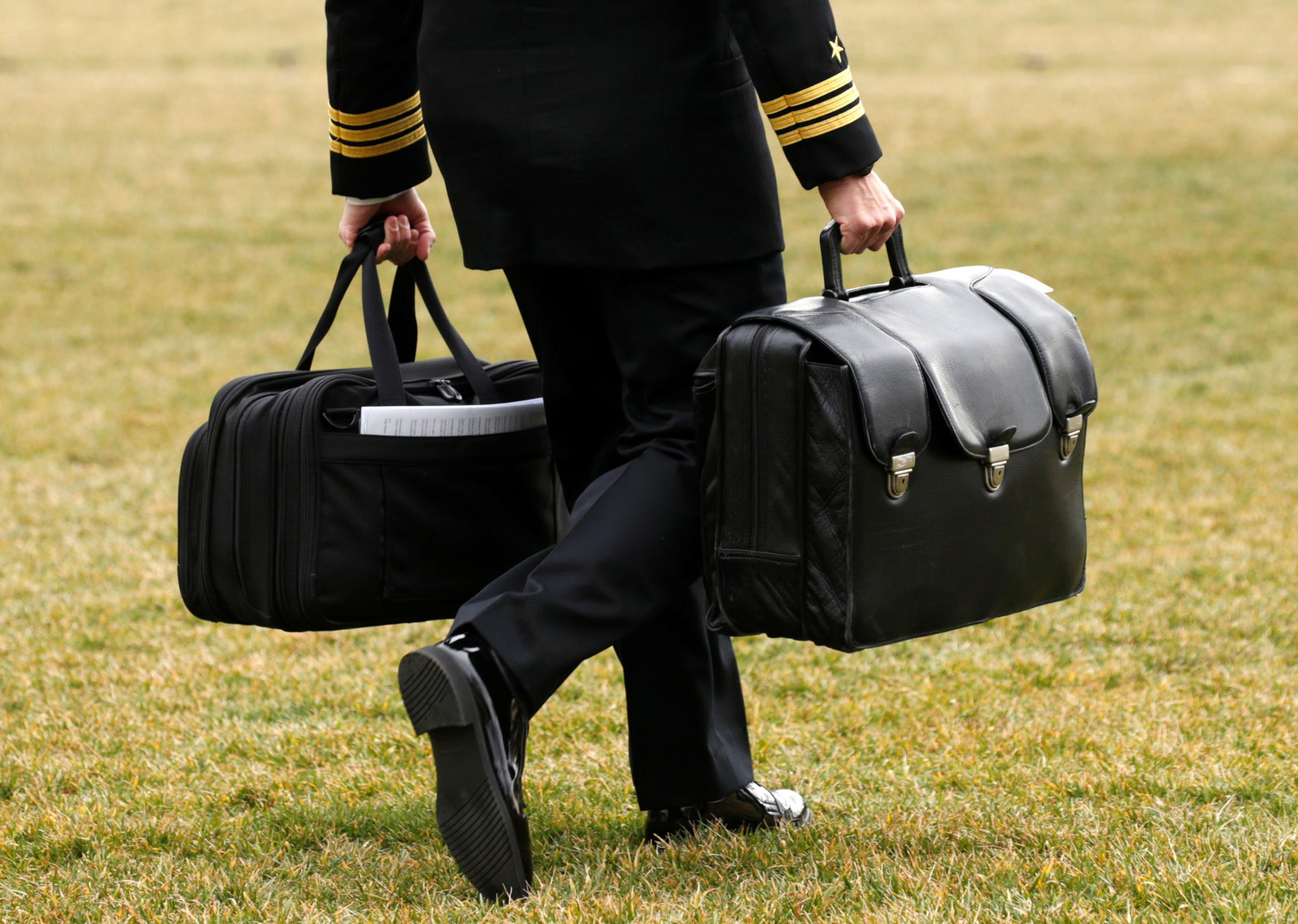 A military aide carries the "football" as Trump departs the White House in Washington