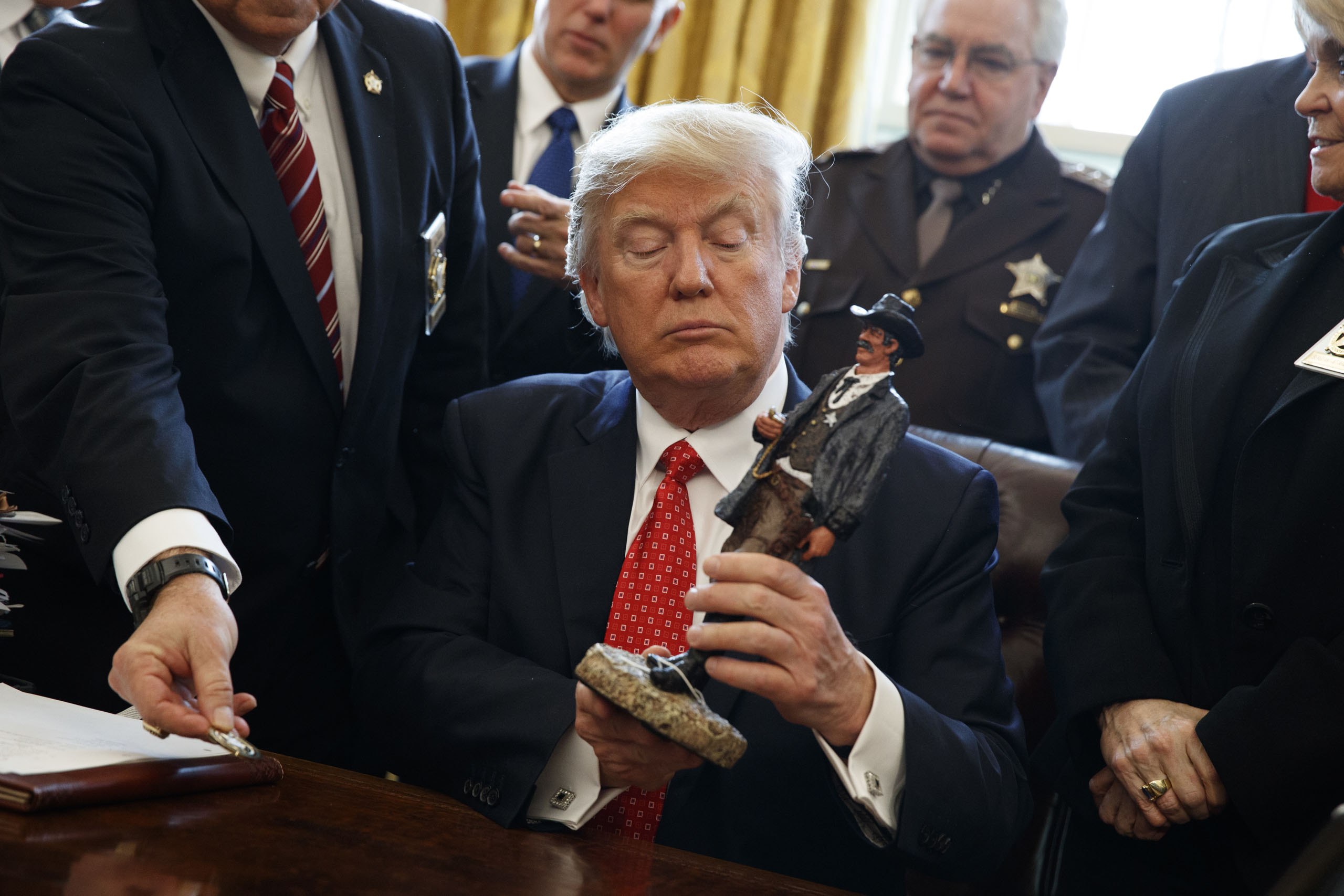 President Donald Trump looks at a figurine given to him by a group of county sheriffs in the Oval Office, on Feb. 7, 2017.