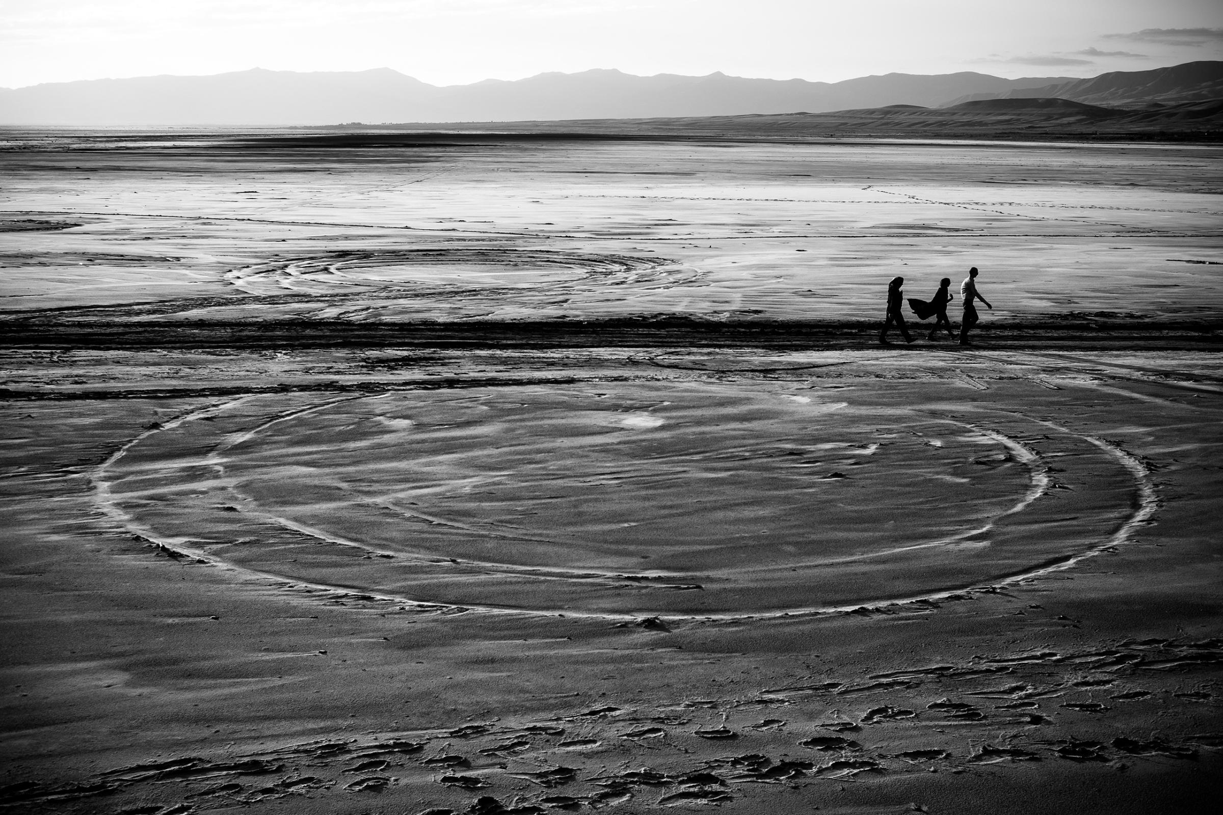 People walk on the dried Lake Urmia in northwestern Iran, near the Turkish border, which was once one of the largest saltwater lakes in the Middle East. The lake has been shrinking  over the last 20 years. This past summer algae and bacteria turned the water red.