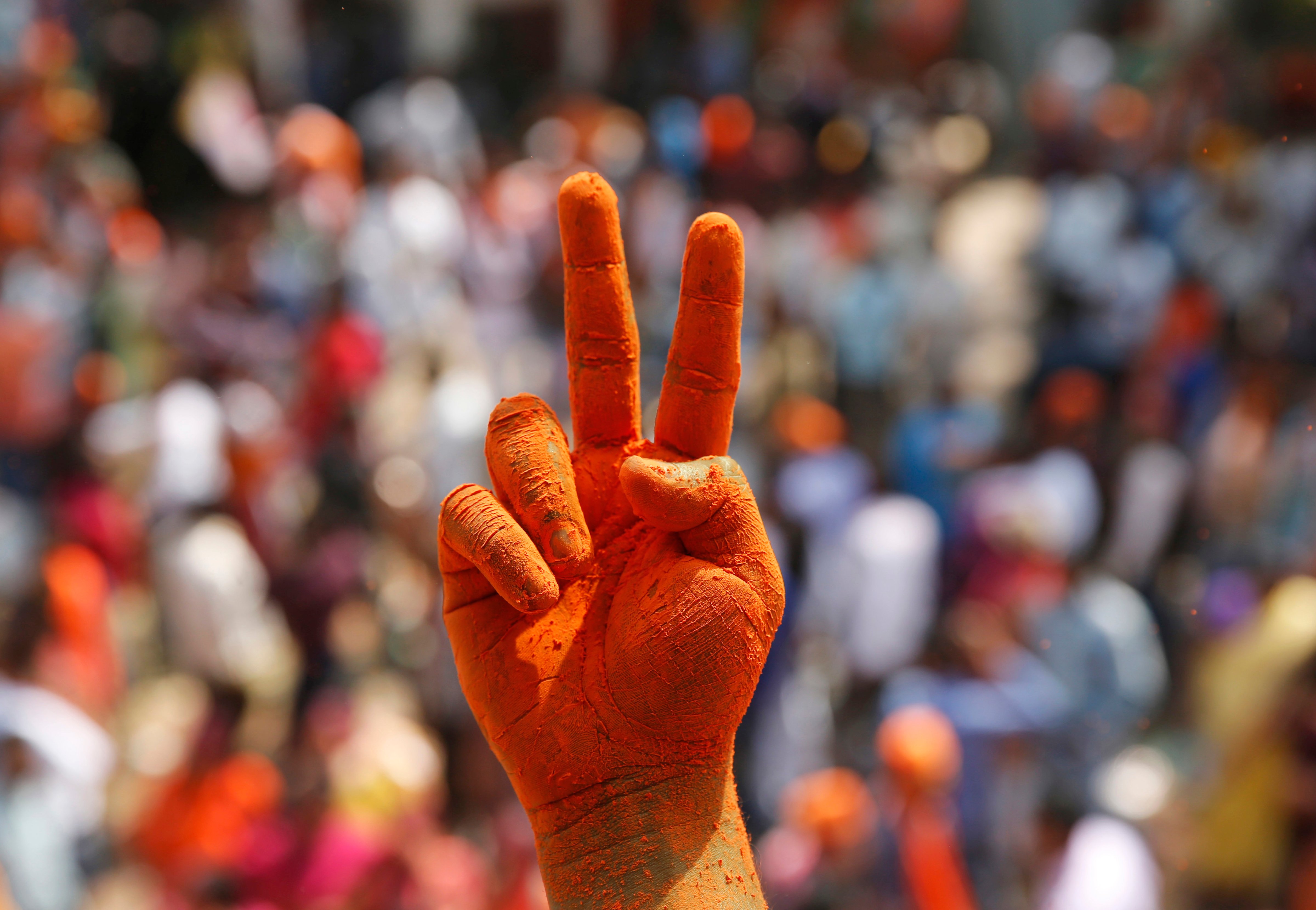 A Bharatiya Janata Party supporter's hands are covered in saffron color as he displays a victory sign in Lucknow, India, on March 11, 2017 (Rajesh Kumar Singh—AP)