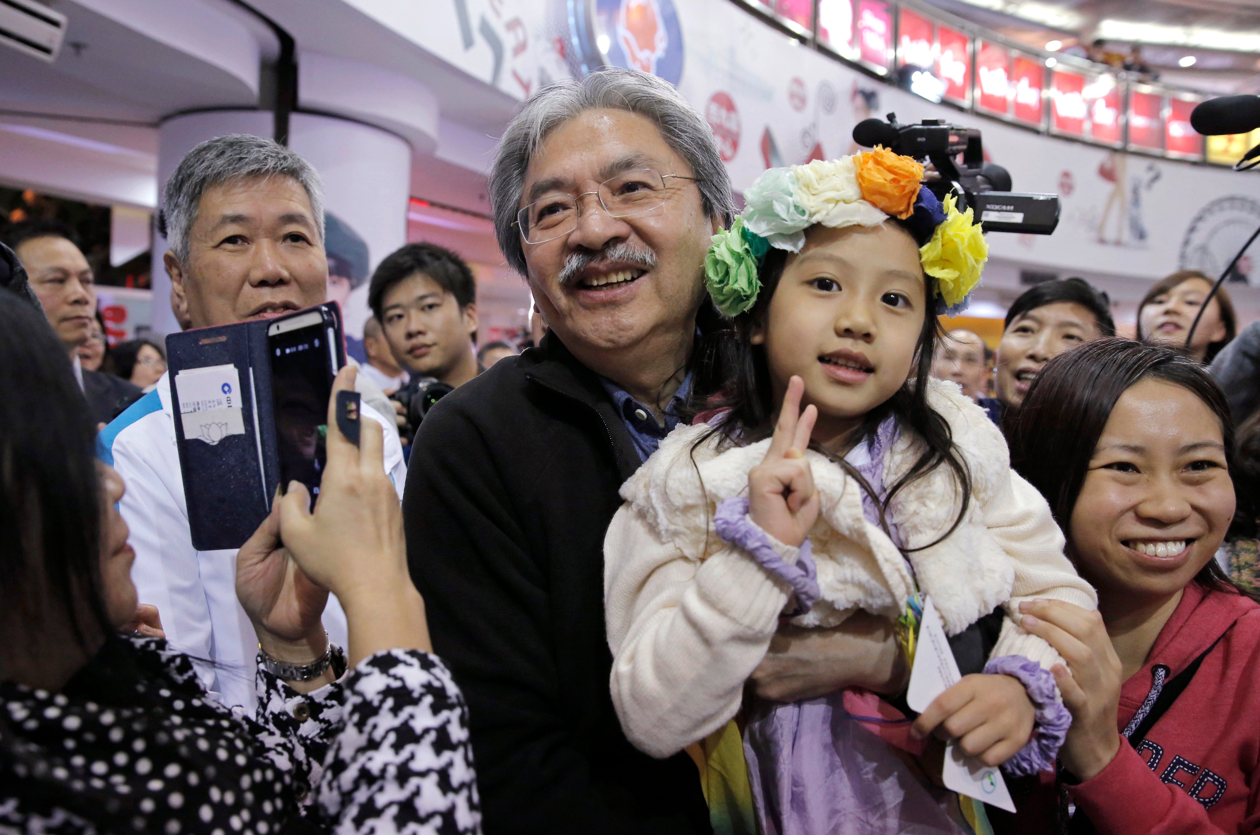 Chief Executive candidate, Hong Kong's former Financial Secretary John Tsang, center, holds a child as he poses for a photograph with his supporters at an election campaign in Hong Kong on March 16, 2017 (Kin Cheung—AP)