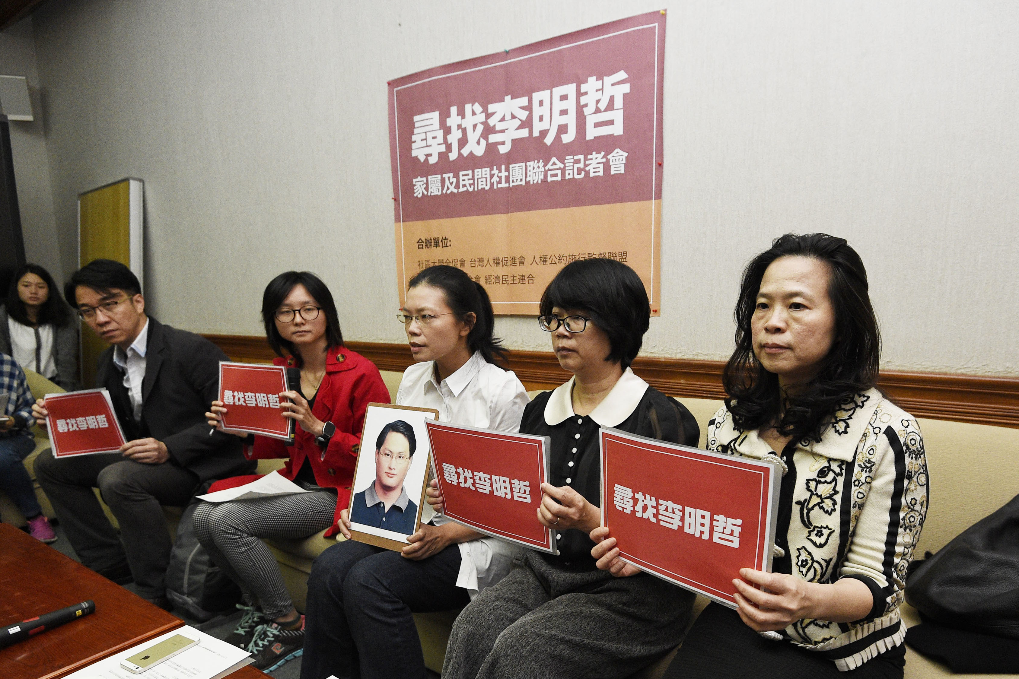 In this photo taken  March 24, 2017, Lee Ching-yu, third from right, holds up a photo of her missing husband, Taiwanese pro-democracy activist Lee Ming-che (AP)