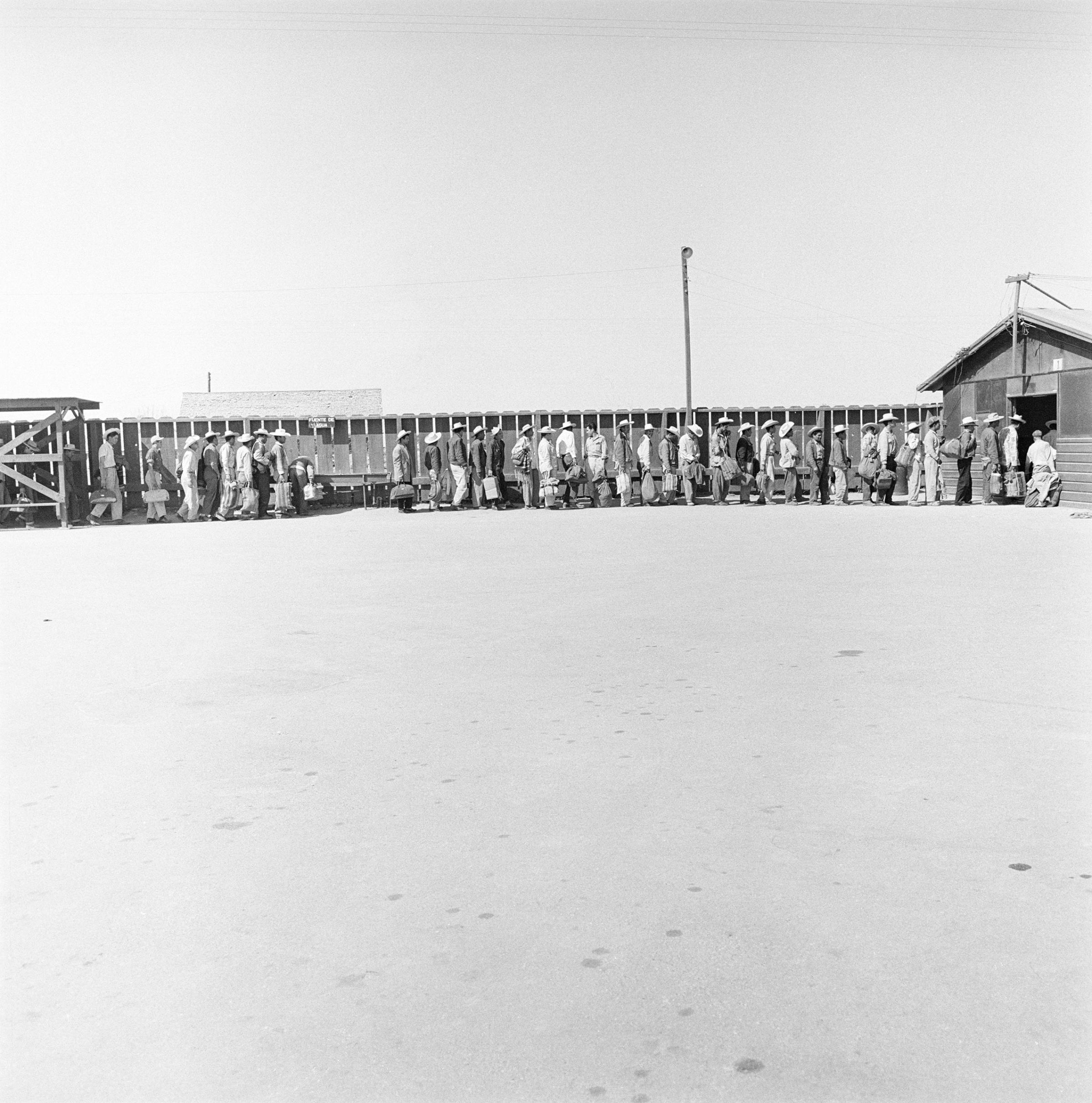 Mexican laborers in line at a reception depot for processing and assignment in California, 1957.