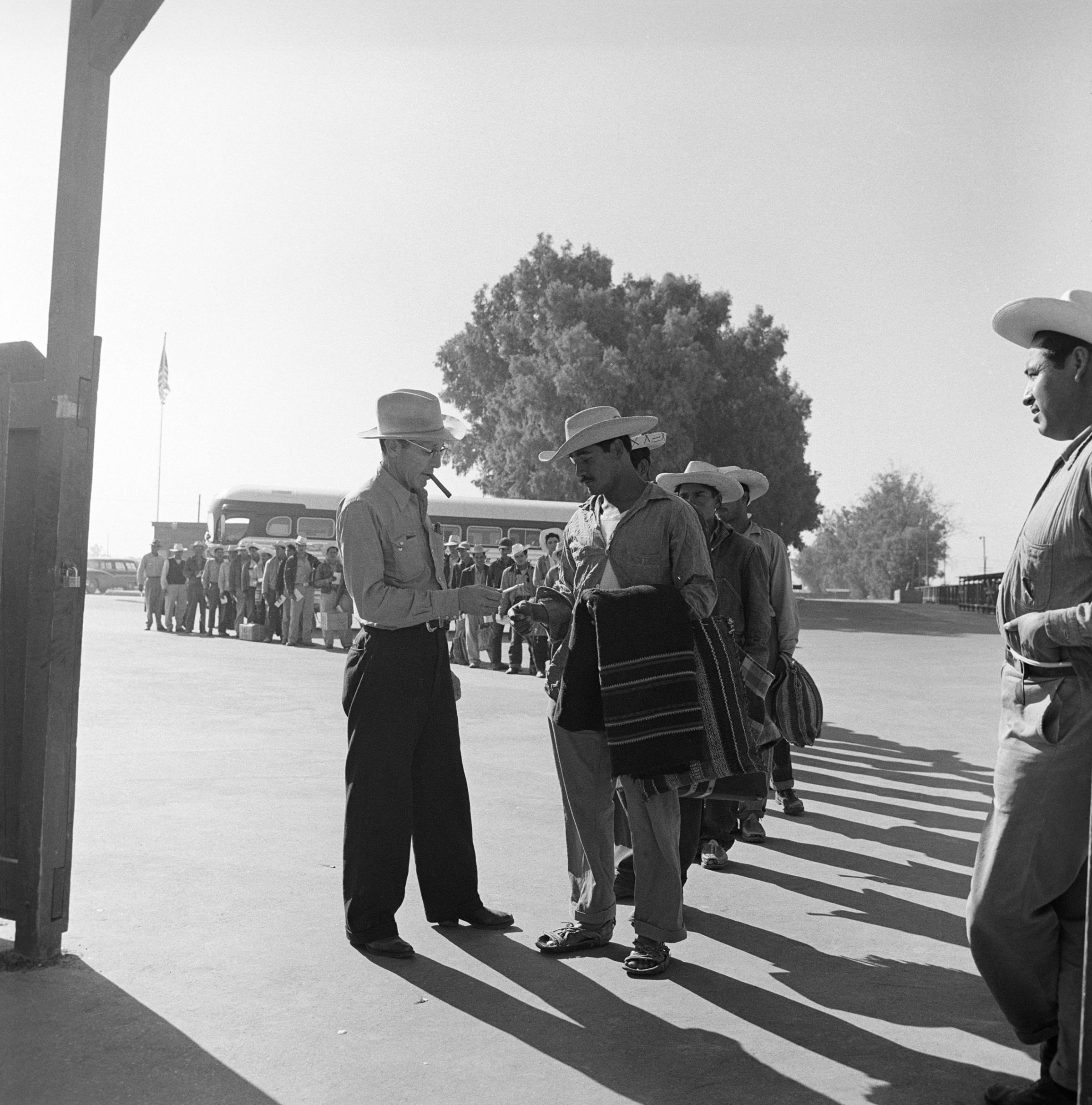 Mexican laborers show their permission to work papers as they arrive at a recruiting center in California, 1957.