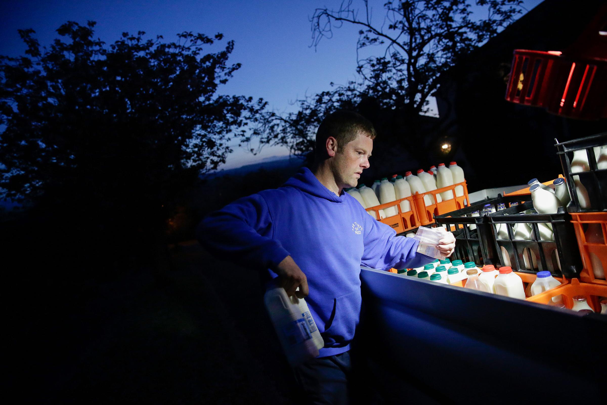 Andrew Thorpe collects milk from his van for an order during his early morning milk doorstep delivery service in Ilkley, Britain, on May 16, 2016.