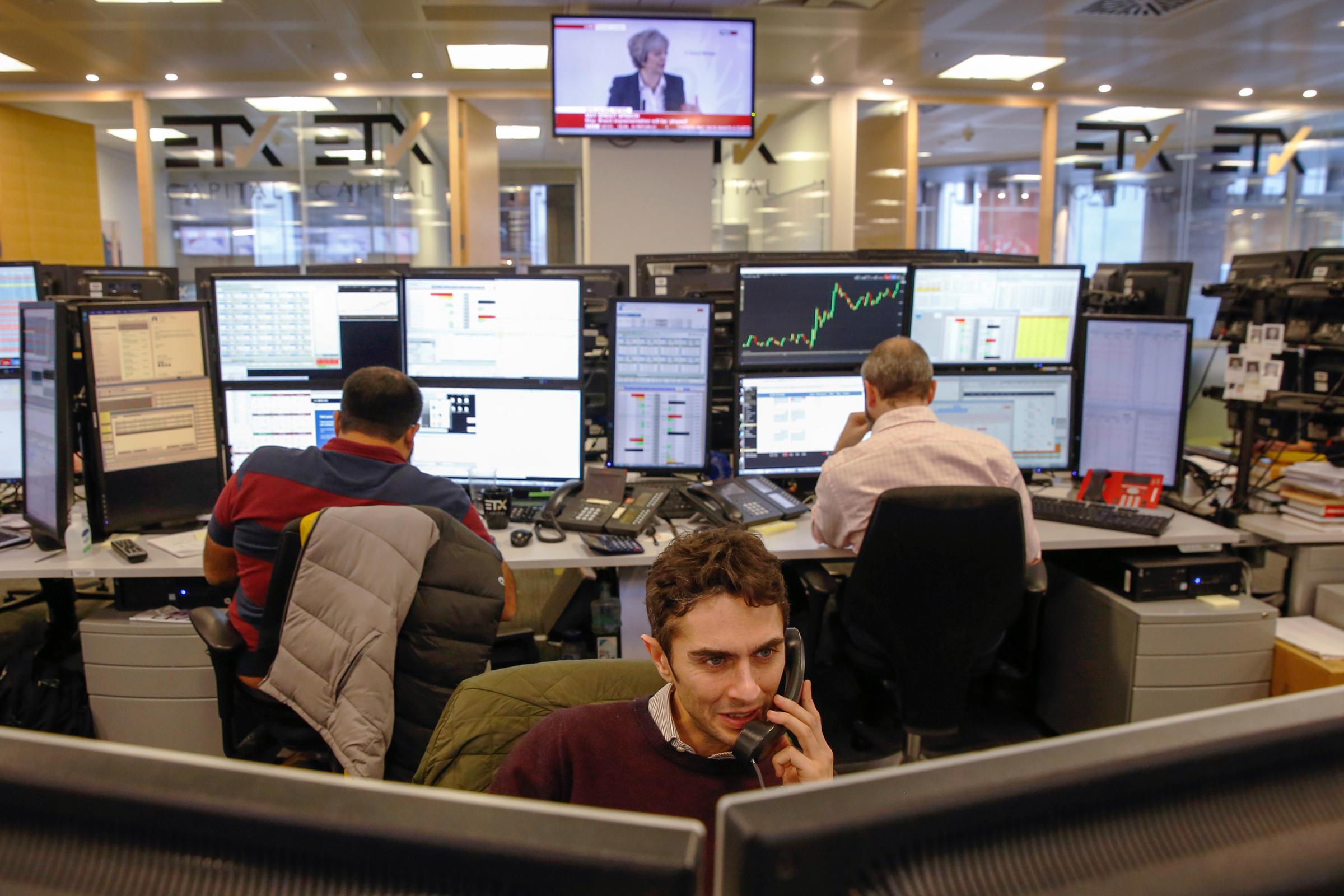 A television displays Theresa May's Brexit speech as traders monitor financial data on the trading floor at broker ETX Capital in London on Jan. 17, 2017.