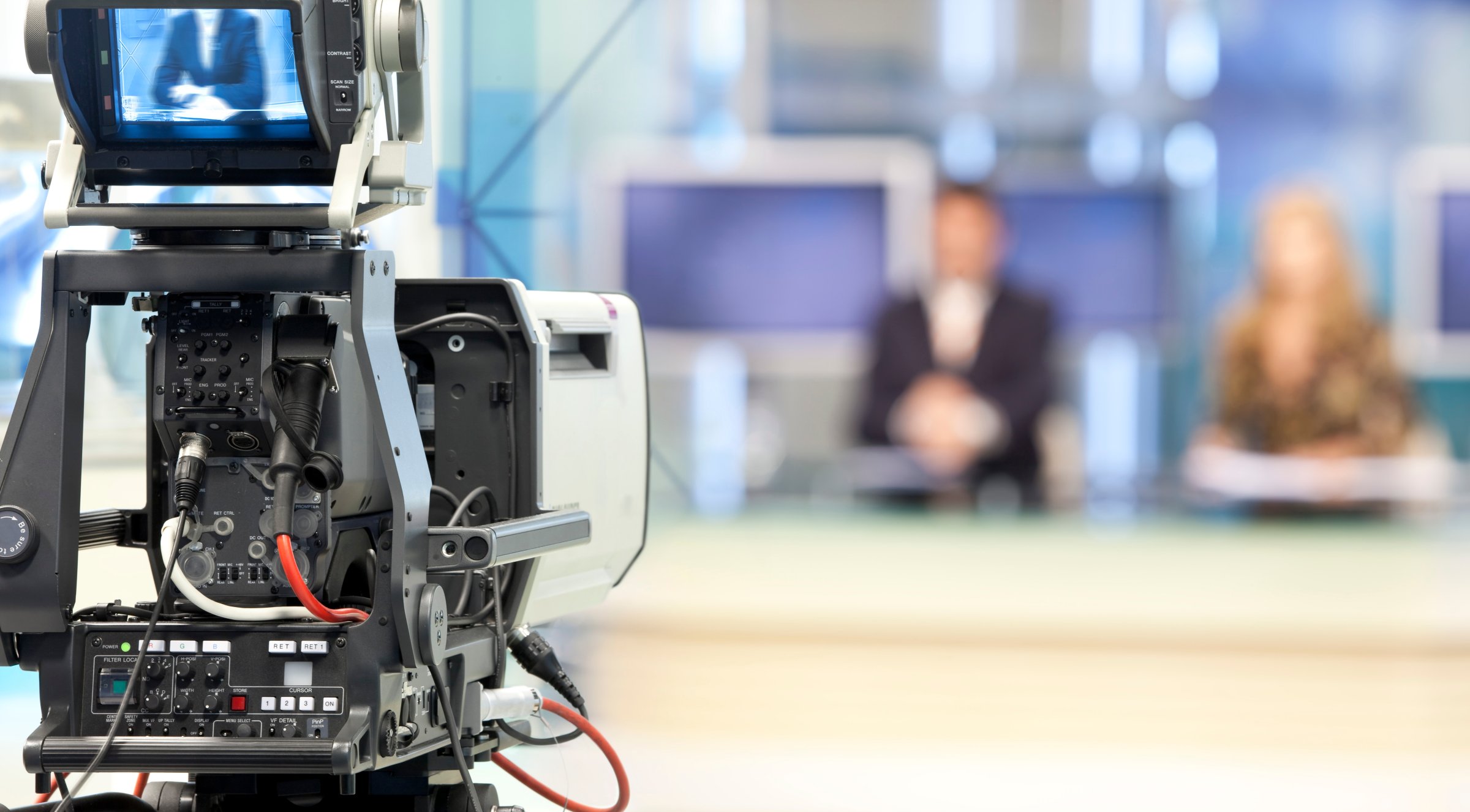newscasters in front of television camera