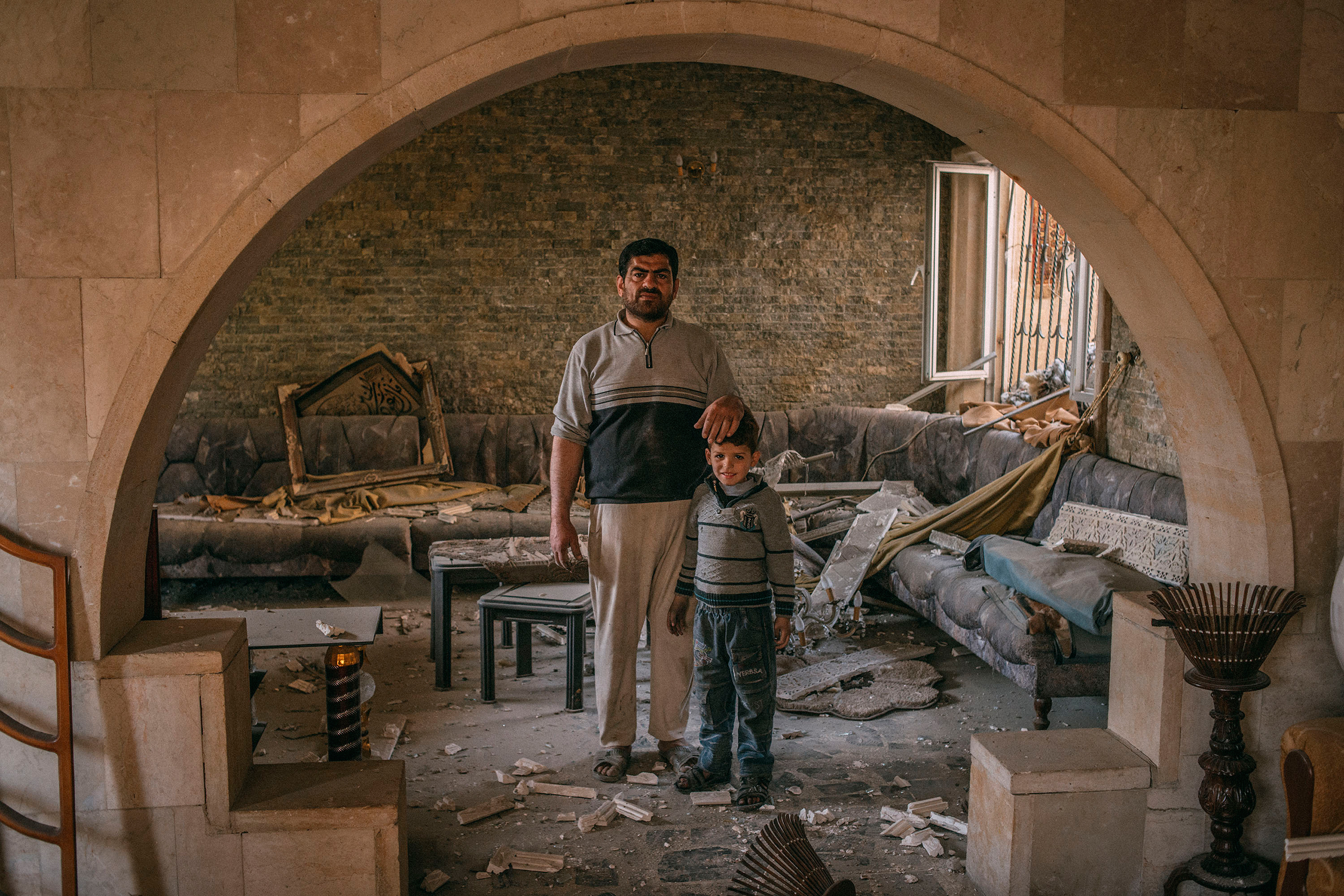 Median Hikmat al-Galou with his son inside their home that was ravaged in February during fighting between Iraqi forces and ISIS in southwest Mosul on March 29, 2017. (Emanuele Satolli for TIME)