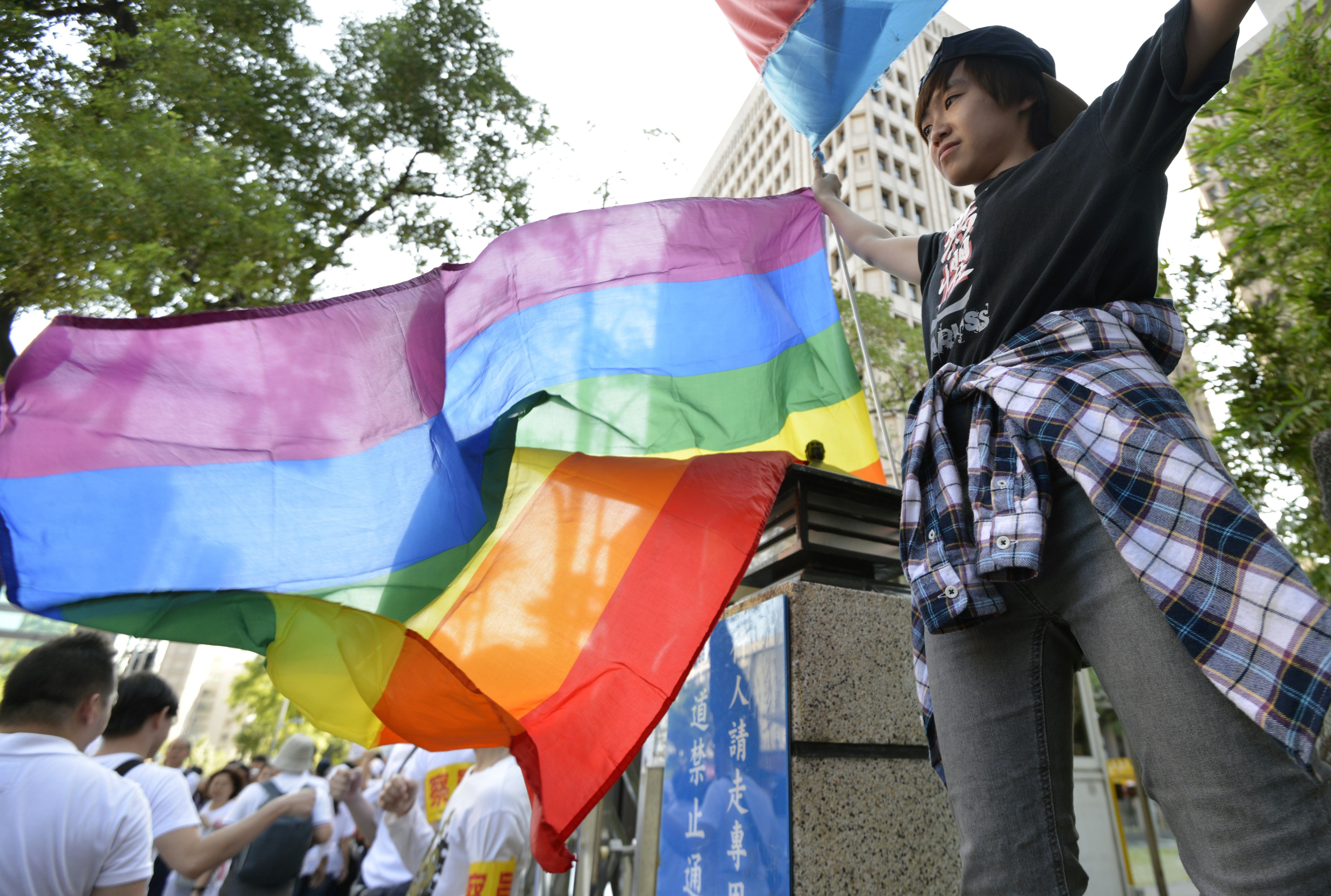 A same-sex marriage supporter displays a rainbow flag outside the parliament in Taipei on Nov.17, 2016 (Sam Yeh—AFP/Getty Images)
