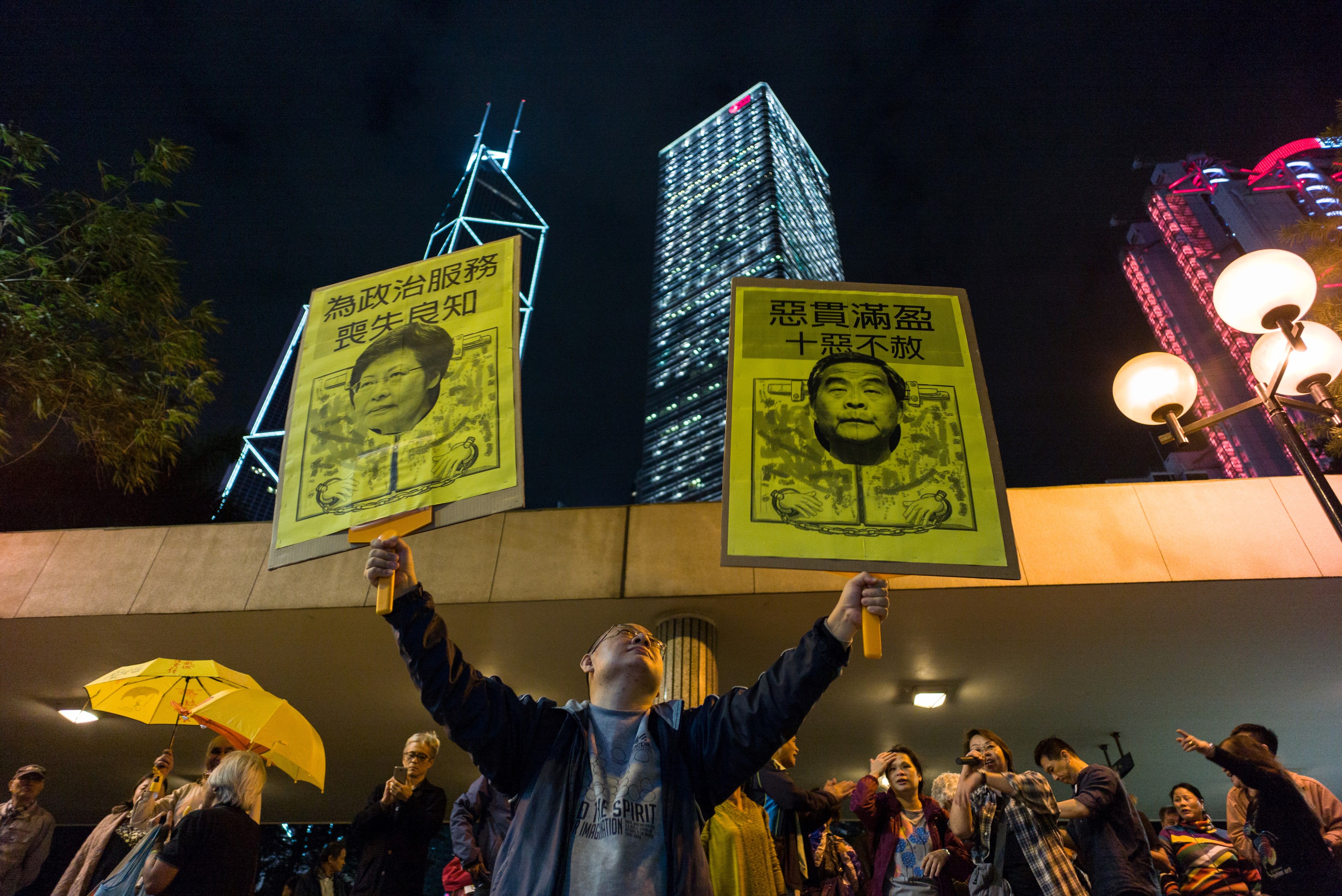 A pro-democracy protester holds up placards featuring Hong Kong's former Chief Secretary Carrie Lam and Chief Executive Leung Chun-ying during a rally in Hong Kong on Dec. 11, 2016 (Anthony Wallace—AFP/Getty Images)