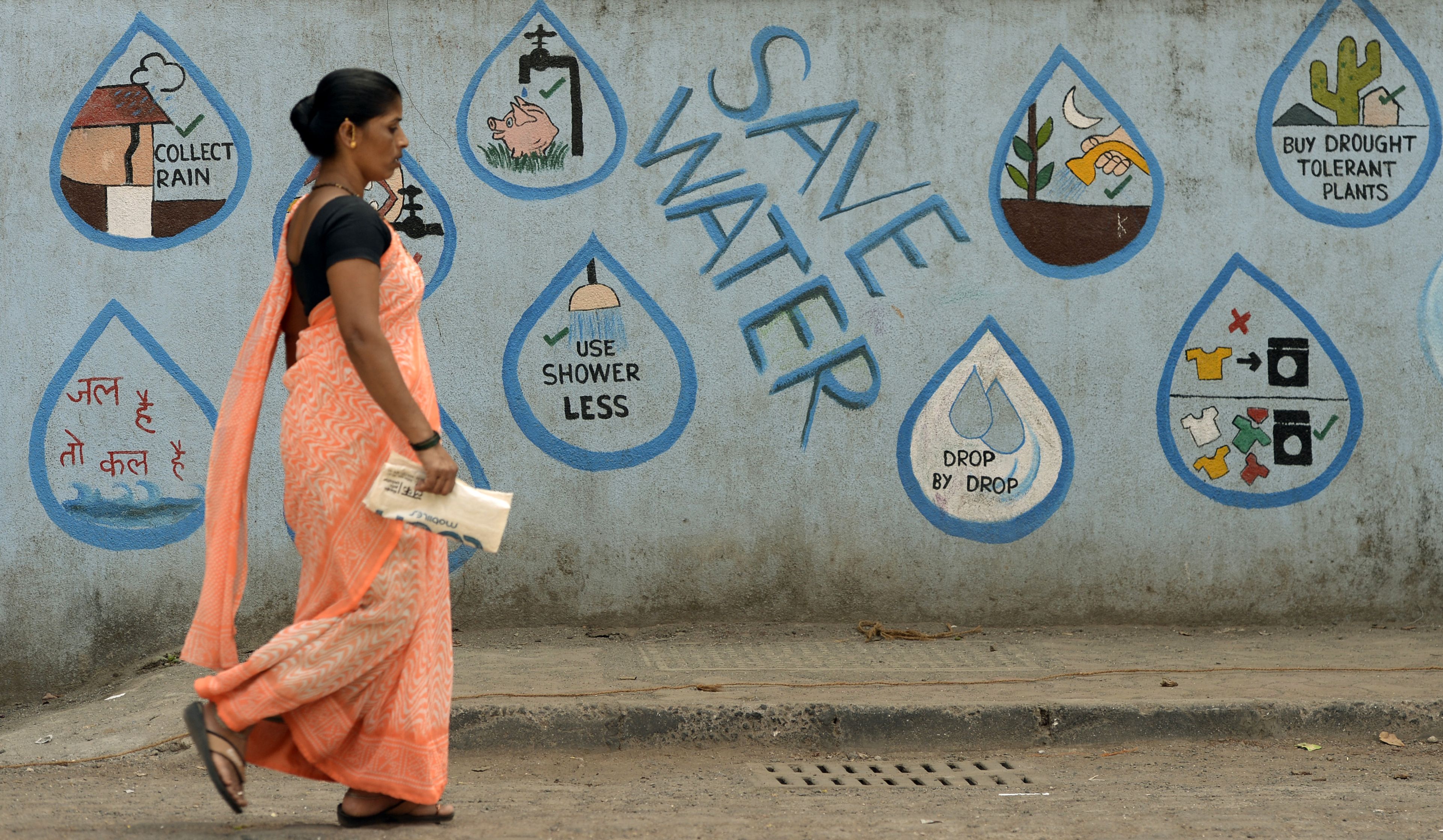 An Indian pedestrian walks past a wall adorned with water conservation messages in Mumbai on March 22, 2017, on World Water Day. (Punit Paranjpe —AFP—Getty Images)