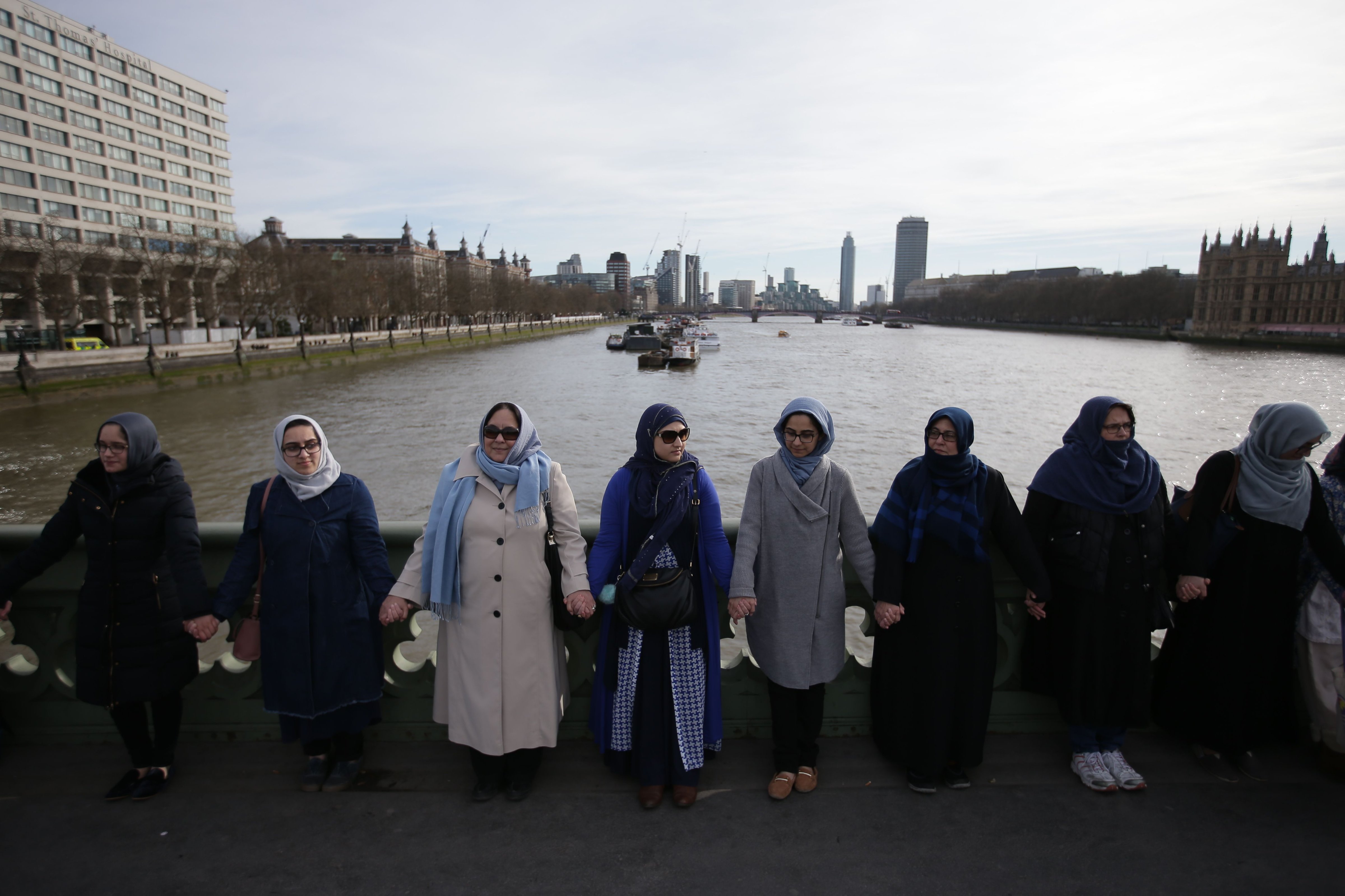 Women activists wearing blue hold hands on Westminster Bridge in front of the Houses of Parliament to honour the victims of the March 22 attack in central London on March 26, 2017. (DANIEL LEAL-OLIVAS—AFP/Getty Images)