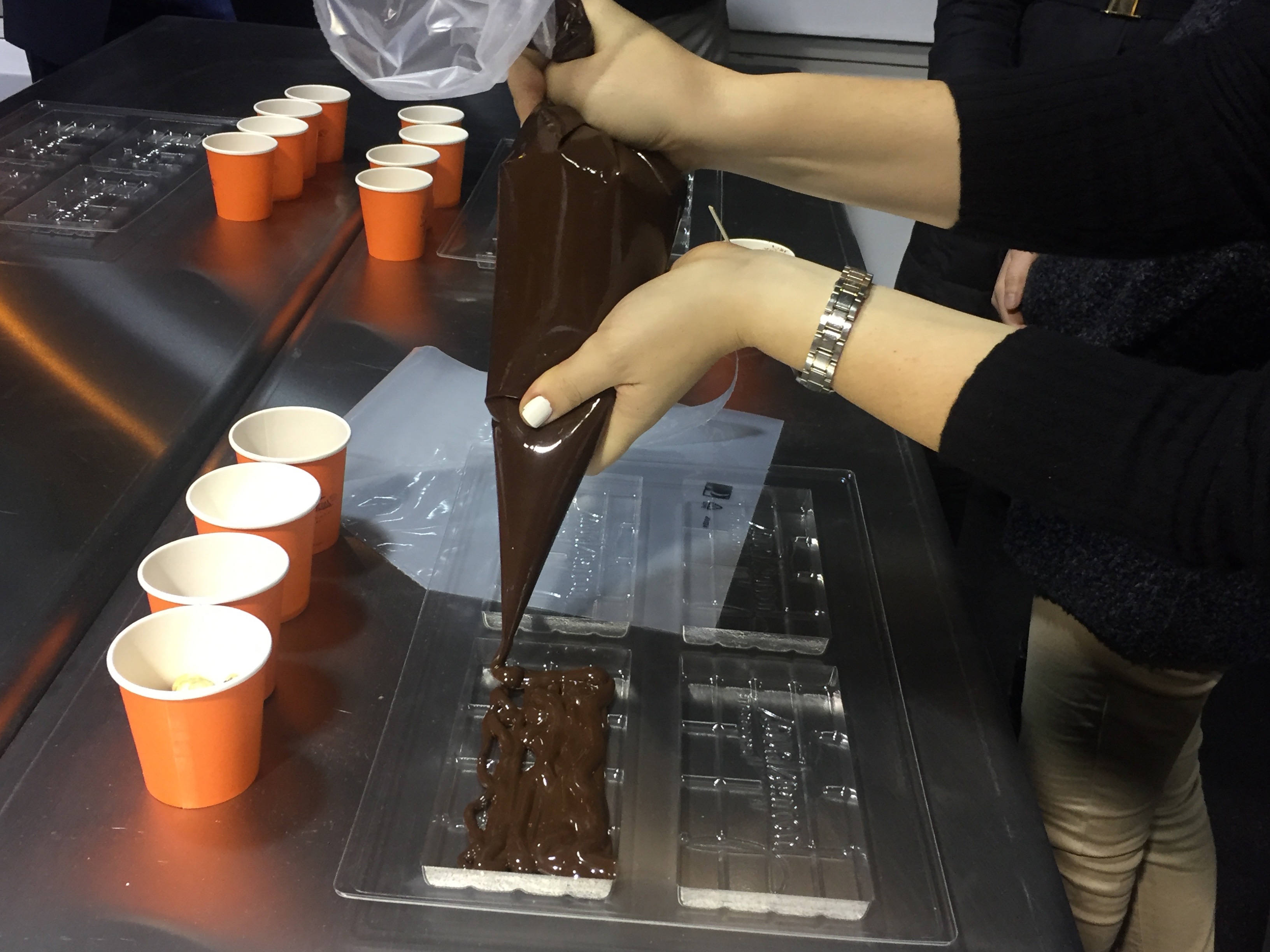 Visitors are guided through the process of filling molds for chocolate bars.