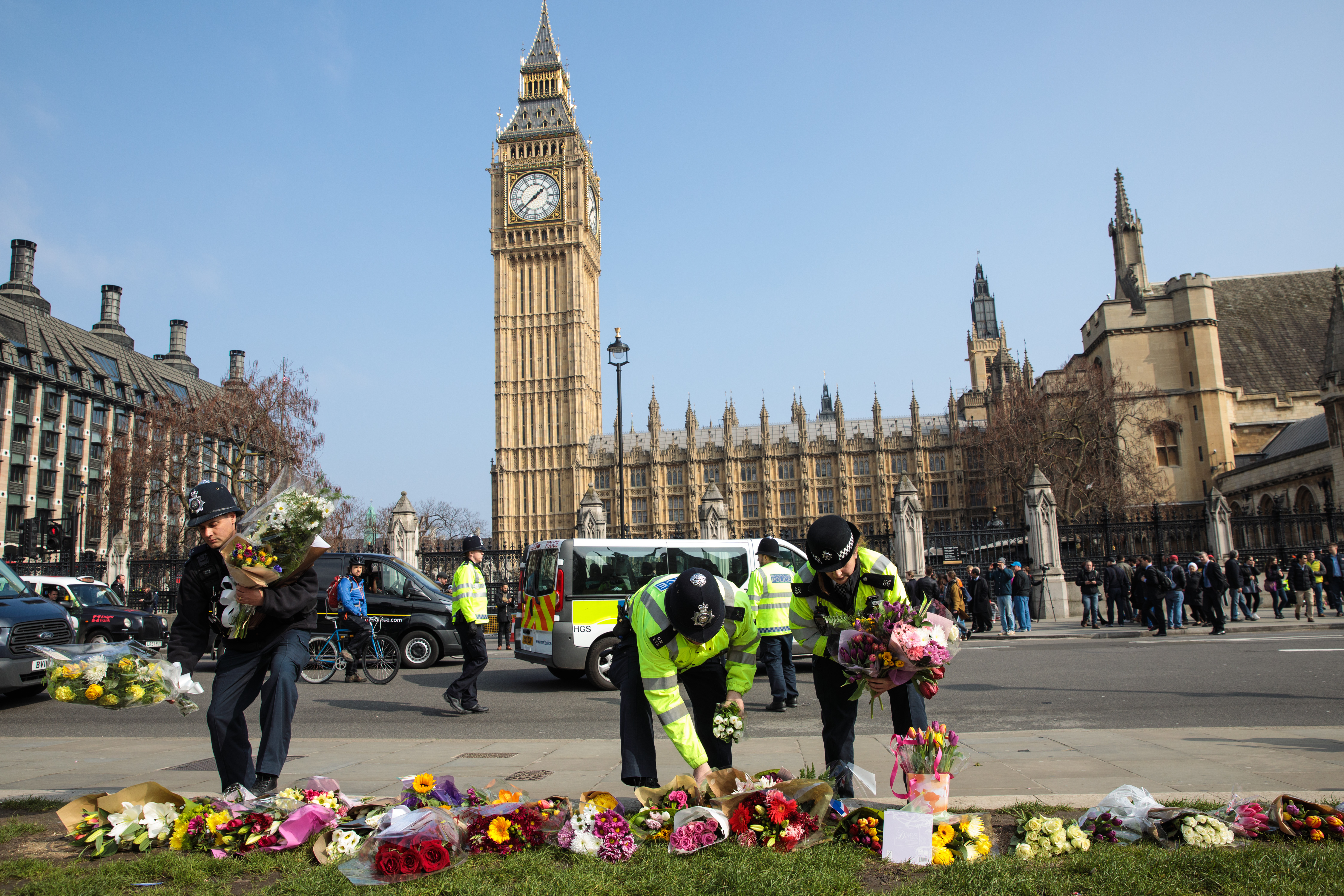 Police officers move floral tributes from outside the Houses of Parliament to Parliament Square after the March 22, 2017, attack on Westminster in London (Jack Taylor&mdash;Getty Images)