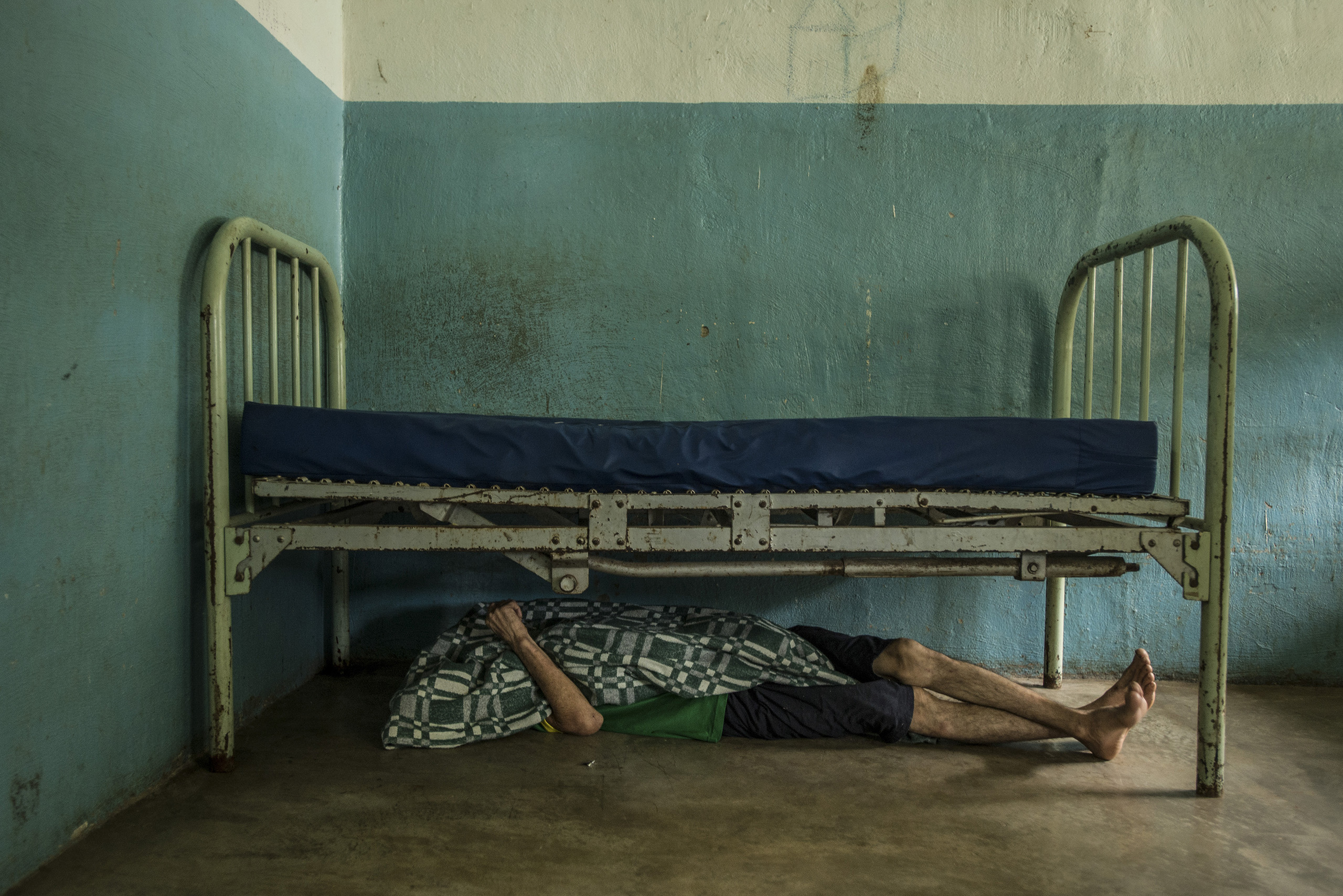 Raul Martinez, who has little medication for his schizophrenia, takes a nap under his bed at the state-run Pampero Psychiatric Hospital in Barquisimeto, Venezuela, on July 28, 2016.