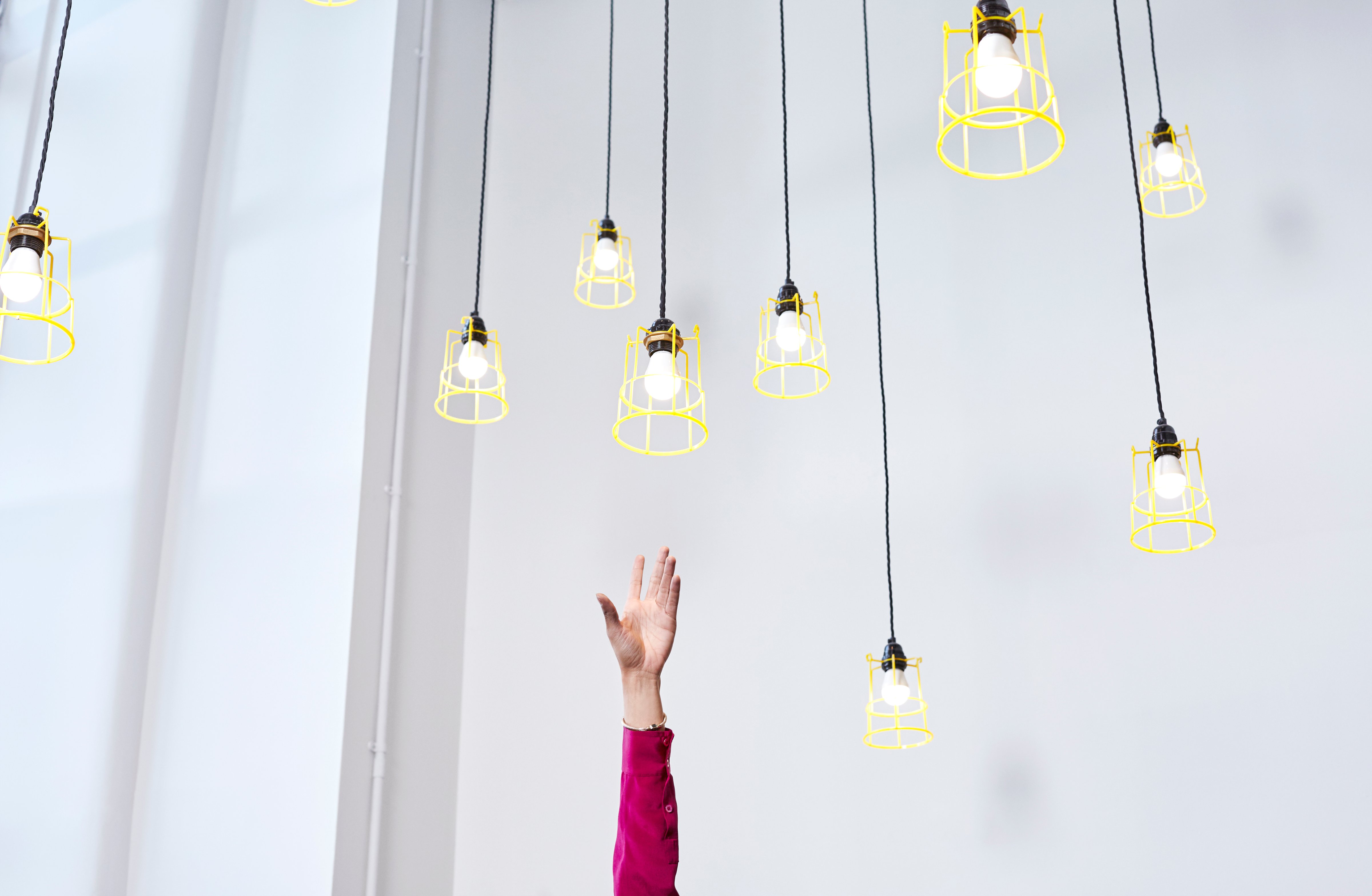 A hand reaching for conceptual idea lightbulbs