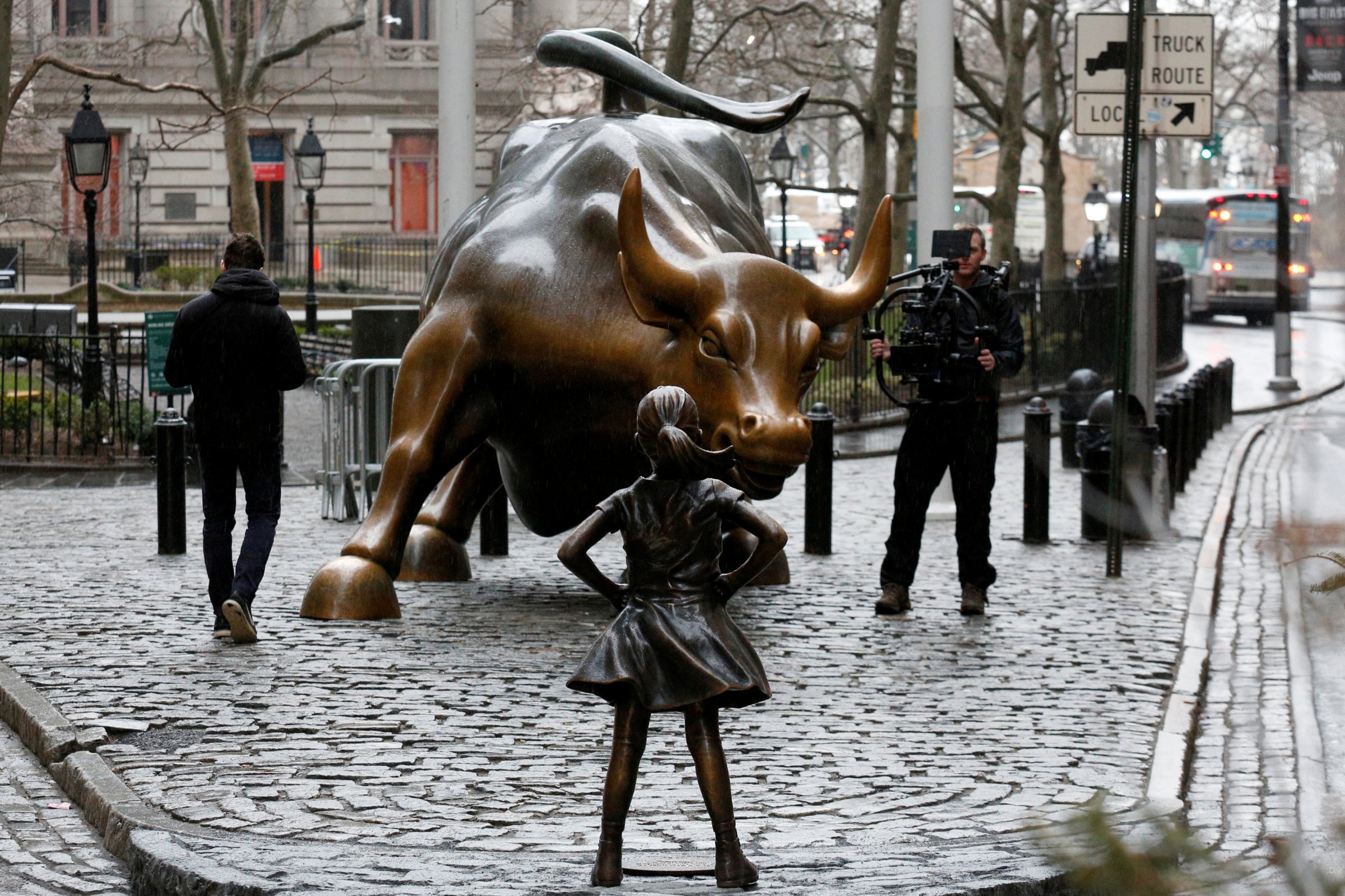 A camera man films a statue of a girl facing the Wall St. Bull, as part of a campaign by U.S. fund manager State Street to push companies to put women on their boards, in the financial district in New York