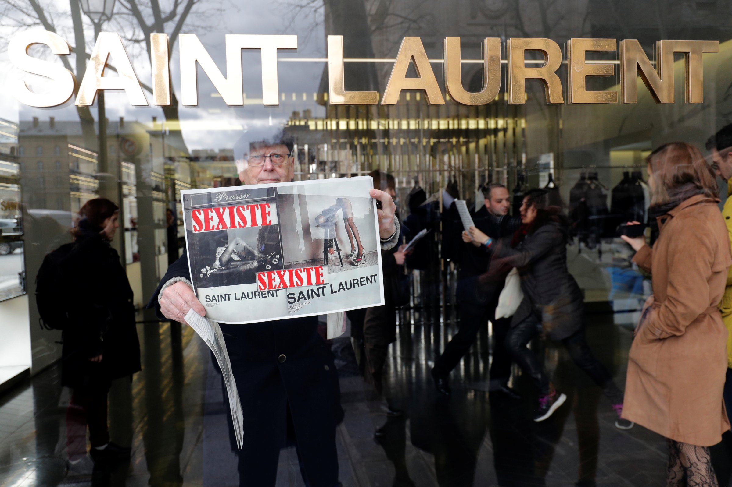 Activists hold placards which read "Sexist" during a demonstration in front of a Yves Saint Laurent shop in Paris