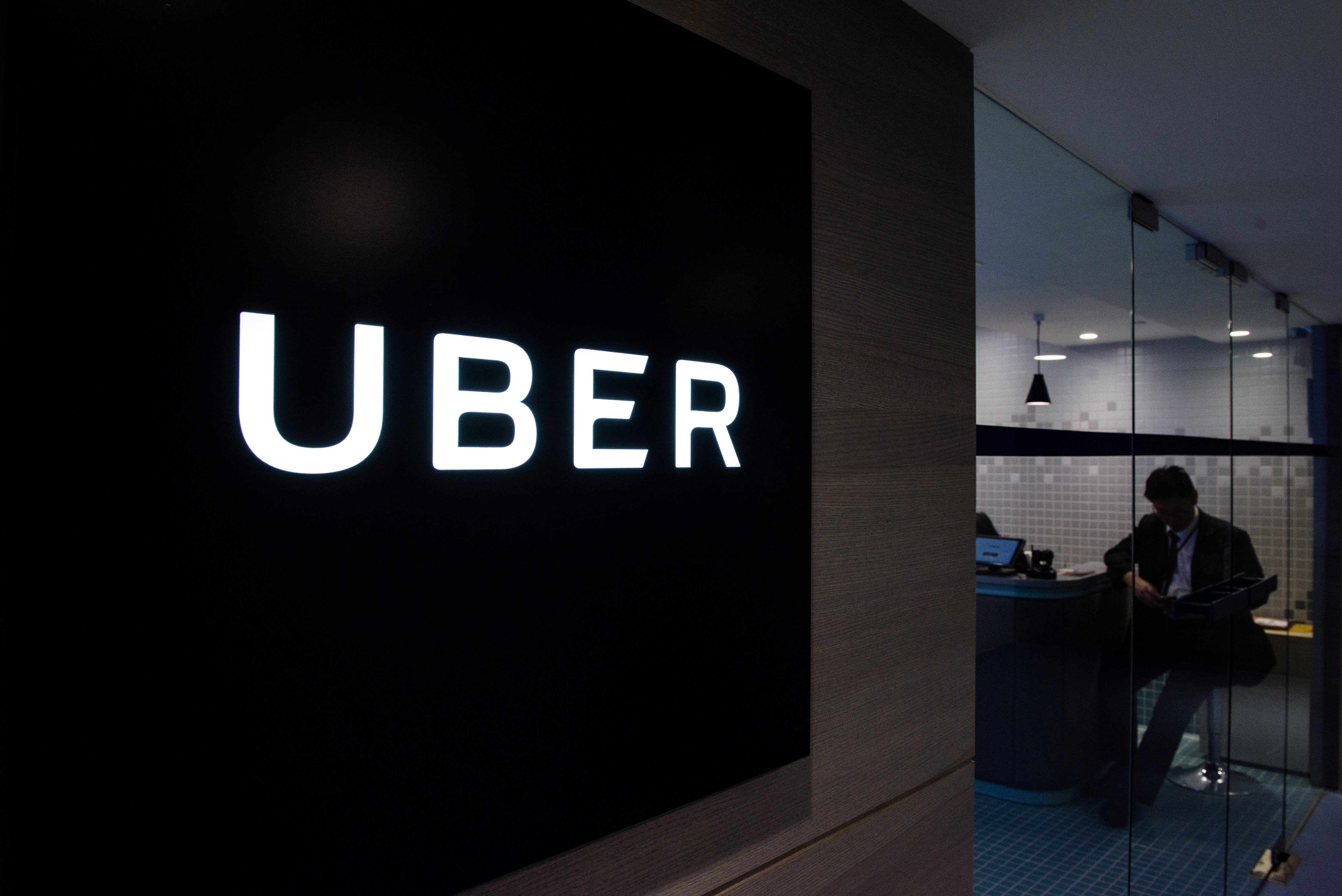 Uber signage is seen as an employee sits in the entrance of the ride-hailing giant's office in Hong Kong on March 10, 2017. (ANTHONY WALLACE&mdash;AFP/Getty Images)