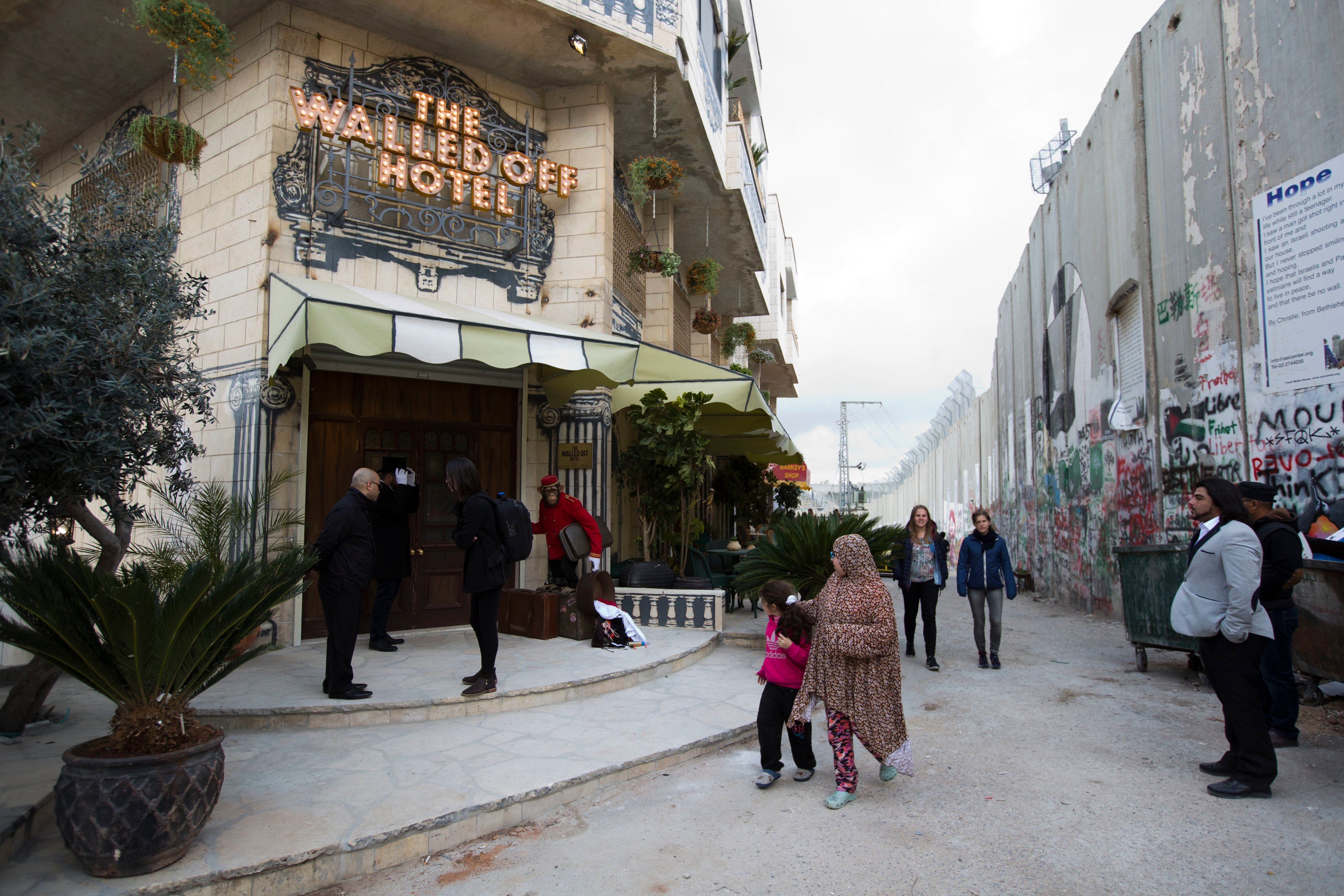 People pass by the "The Walled Off Hotel" and the Israeli security barrier in the West Bank city of Bethlehem, on March 3, 2017. (Dusan Vranic—AP)