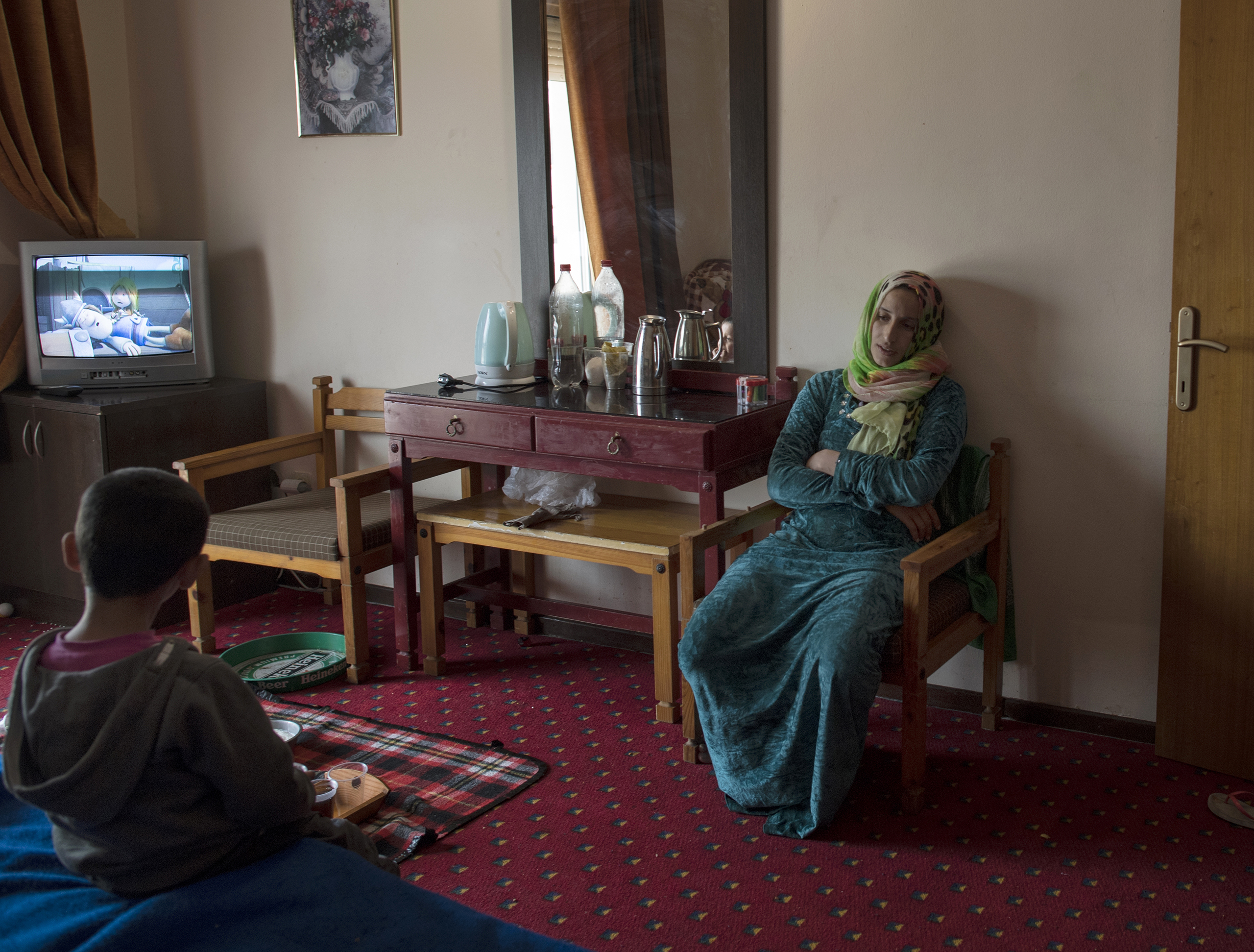 27-year-old Illham Saleh rests for a moment while her third son, Saleh, watches television, at a hotel in kastoria, Greece, near the Albanian border, March 27, 2017.