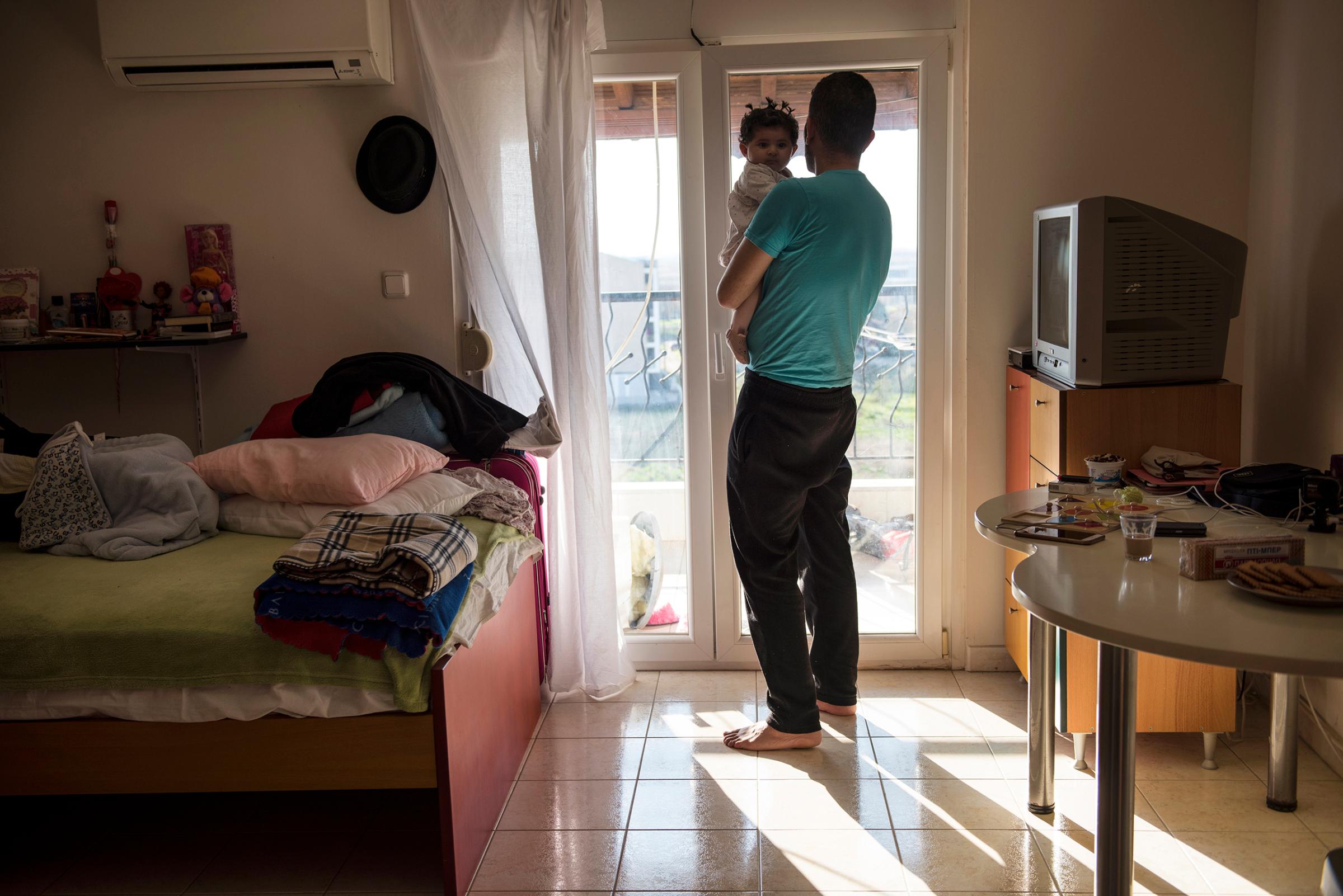 Yousuf Arsan, 27, sings to baby Rahaf, almost 6 months, while his wife (not shown) Noor Al Talaa, 22, cooks lunch at an apartment in Sidros, outside of Thessaloniki, Greece, March 28, 2017.