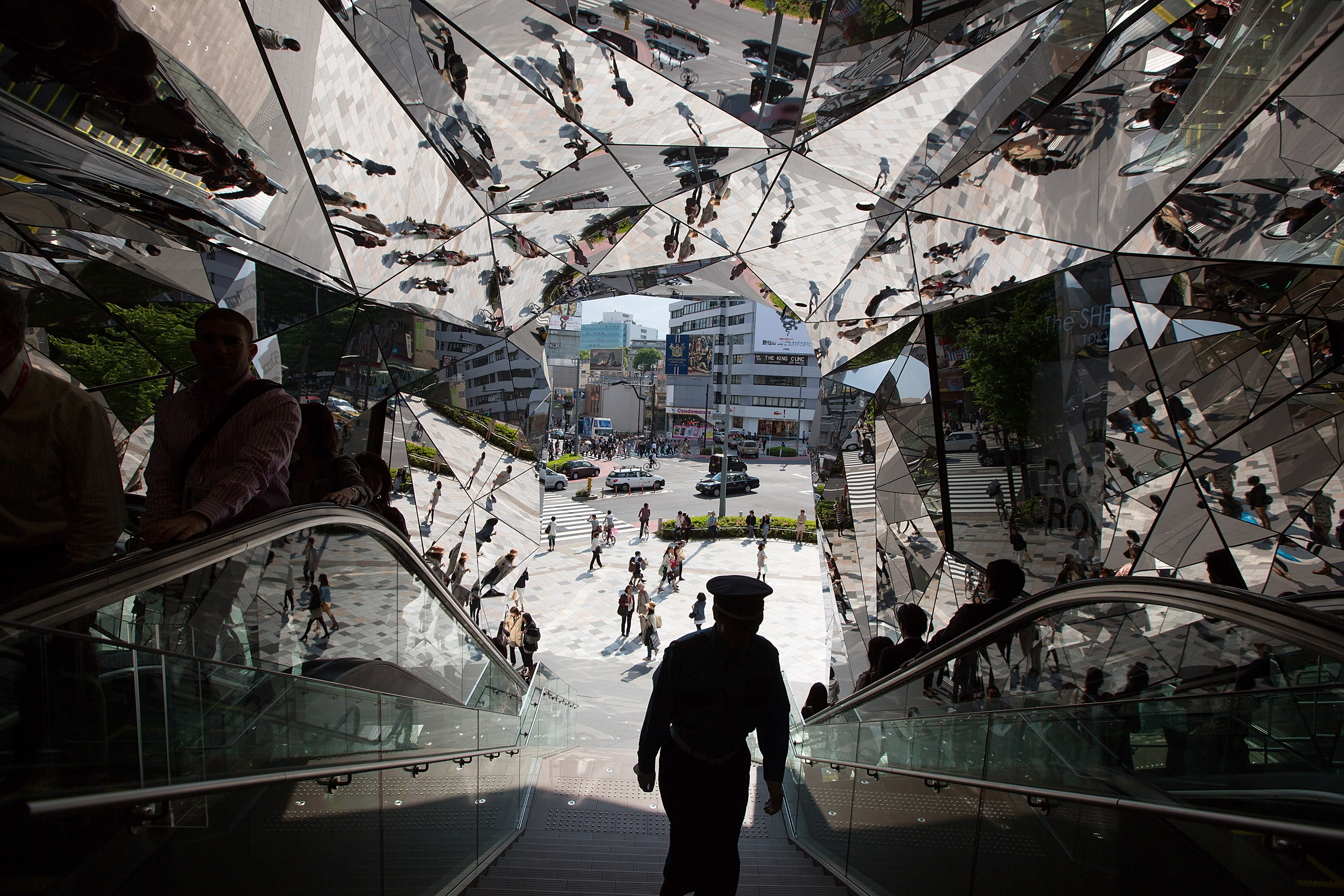 Japanese shoppers and a security guard are reflected in the entrance to the 'Tokyu Plaza Omotesando Harajuku' shopping complex in Tokyo on May 11, 2012. (Jeremy Sutton-Hibbert—Getty Images)