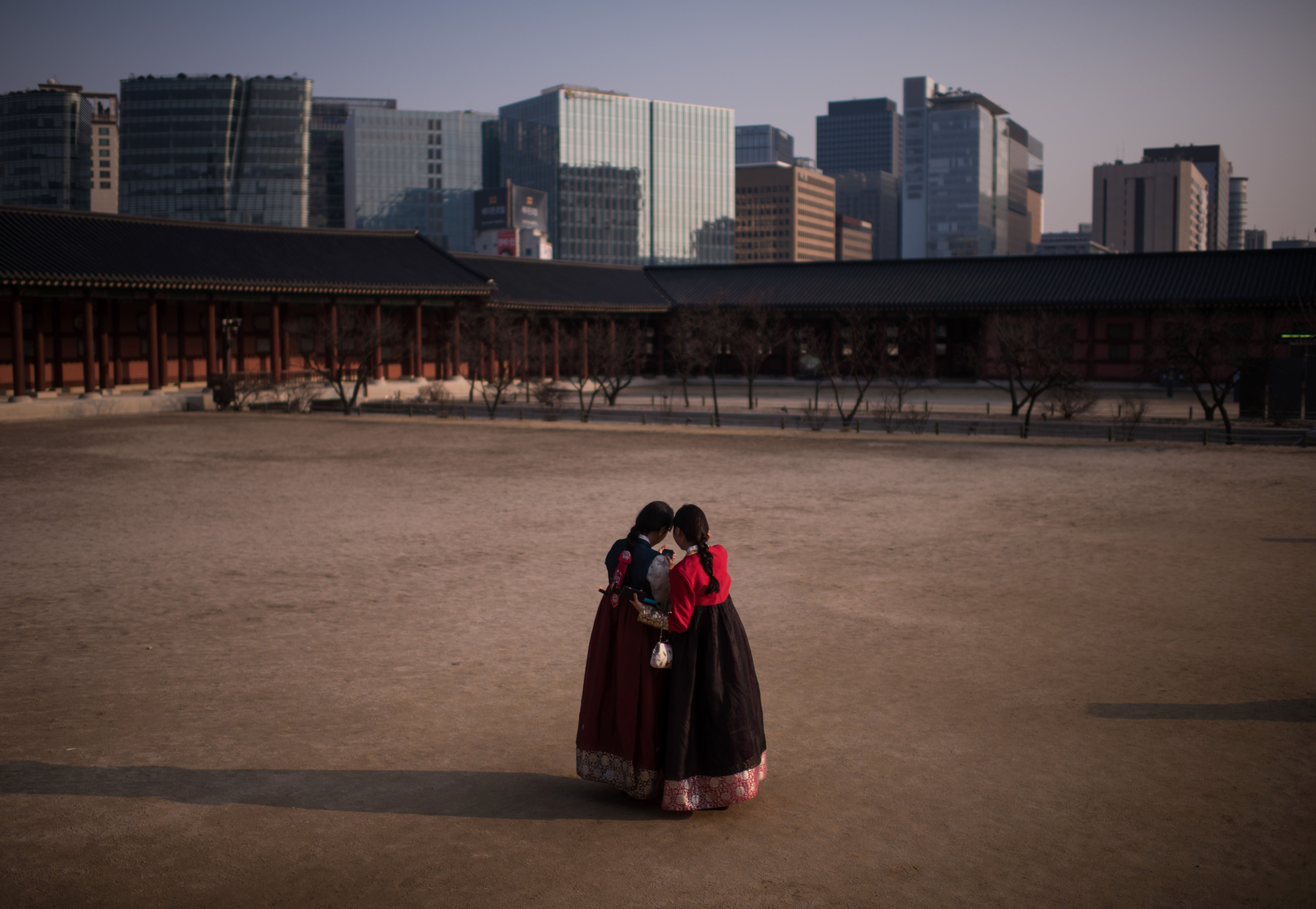 Two women wearing traditional Korean Hanbok dresses pose for selfies at Gyeongbokgung palace in central Seoul on March 2, 2016. (ED JONES/AFP—Getty Images)
