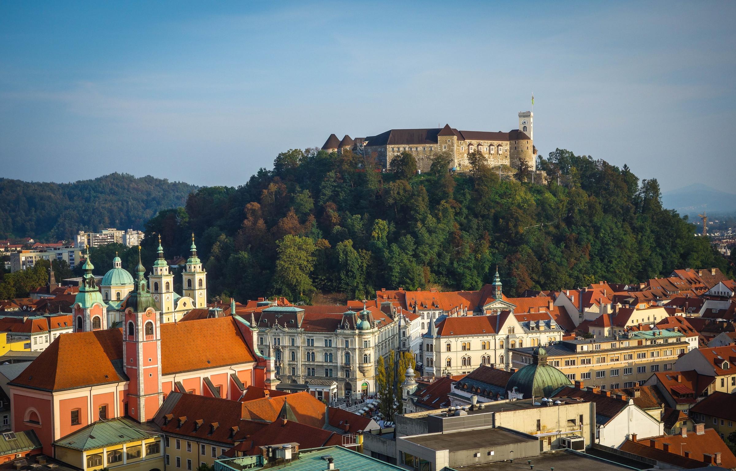 Slovenia, Ljubljana, Castle on wooded hill and surrounding cityscape