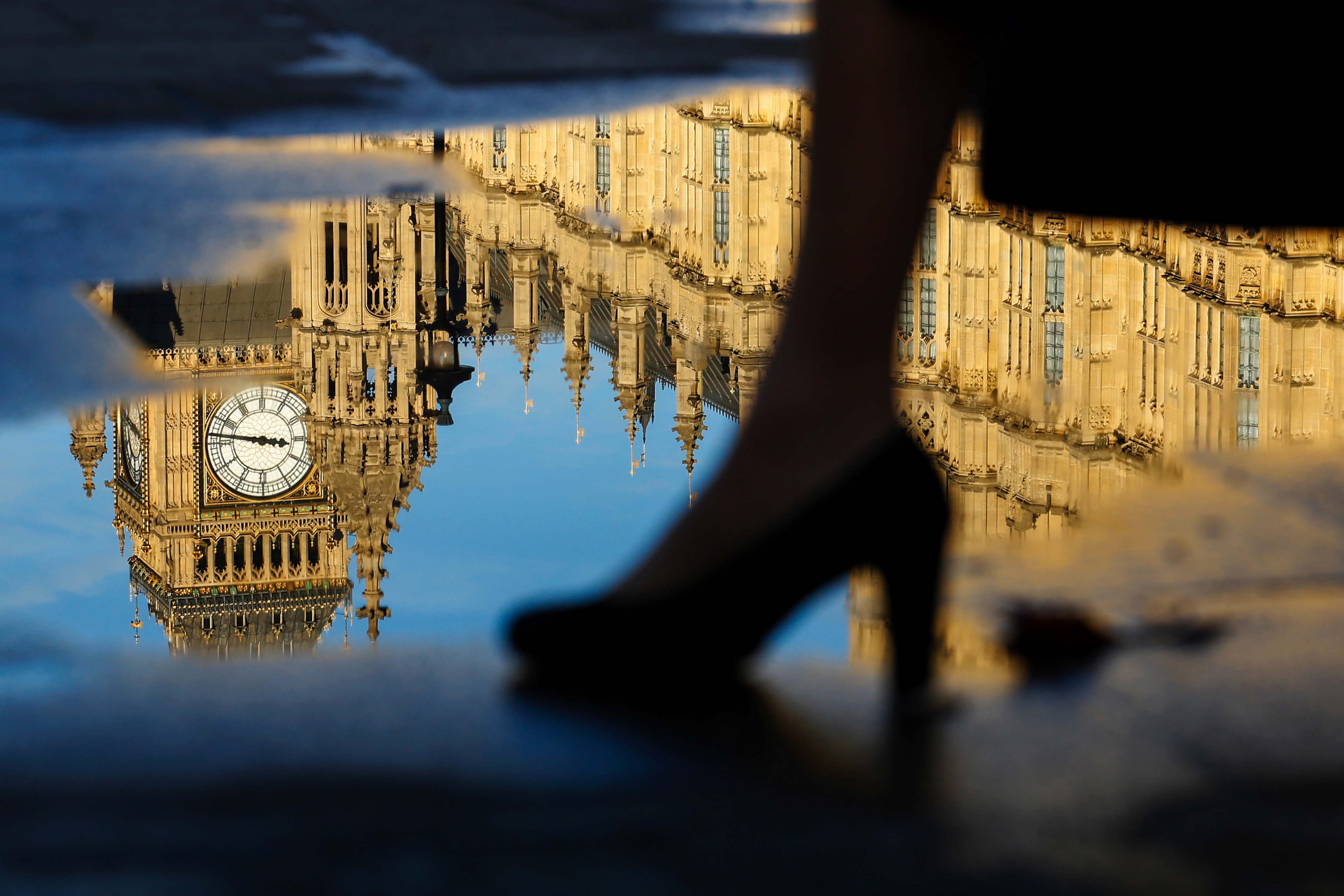 A woman passes a puddle reflecting Elizabeth Tower, commonly referred to as Big Ben, and Houses of Parliament in London, U.K. on Tuesday Jan. 17, 2017. (Luke MacGregor—Bloomberg via Getty Images)