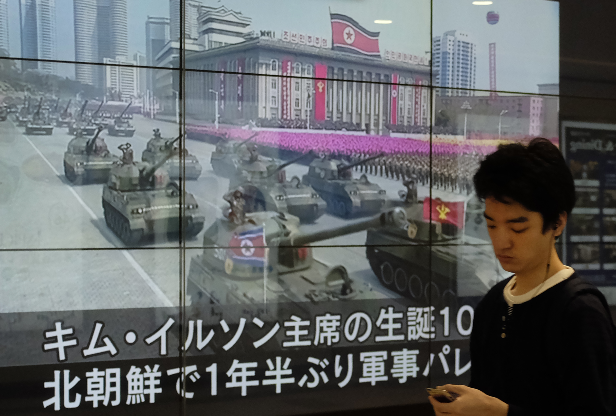 A man in Tokyo walks in front of a news video reporting a military parade marking the 105th anniversary of the birth of late North Korean leader Kim Il Sung on April 16, 2017. (Kazuhiro Nogi—AFP/Getty Images)