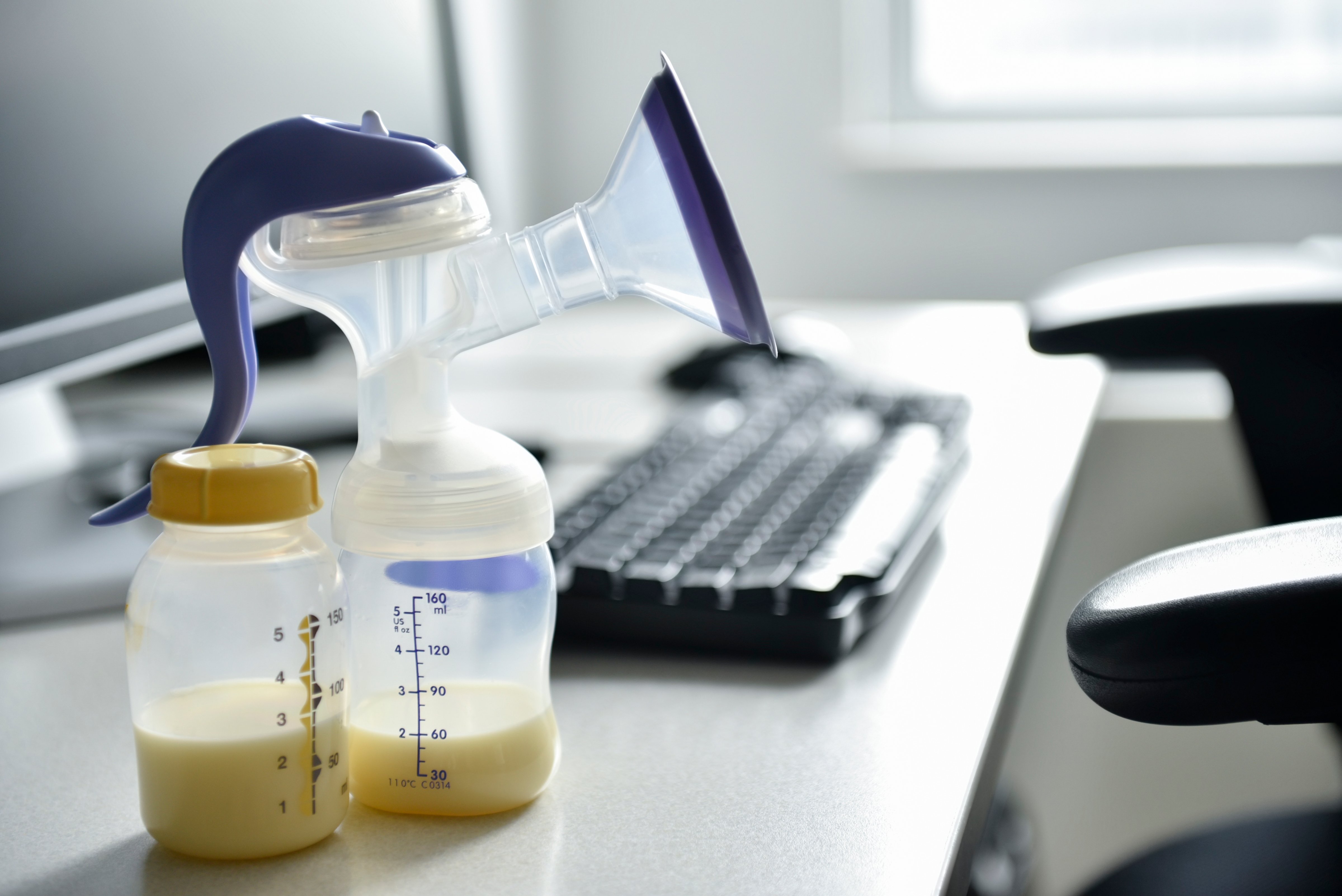 Breast pump and bottle of breast milk near computer (JGI/Jamie Grill&mdash;Getty Images/Blend Images)