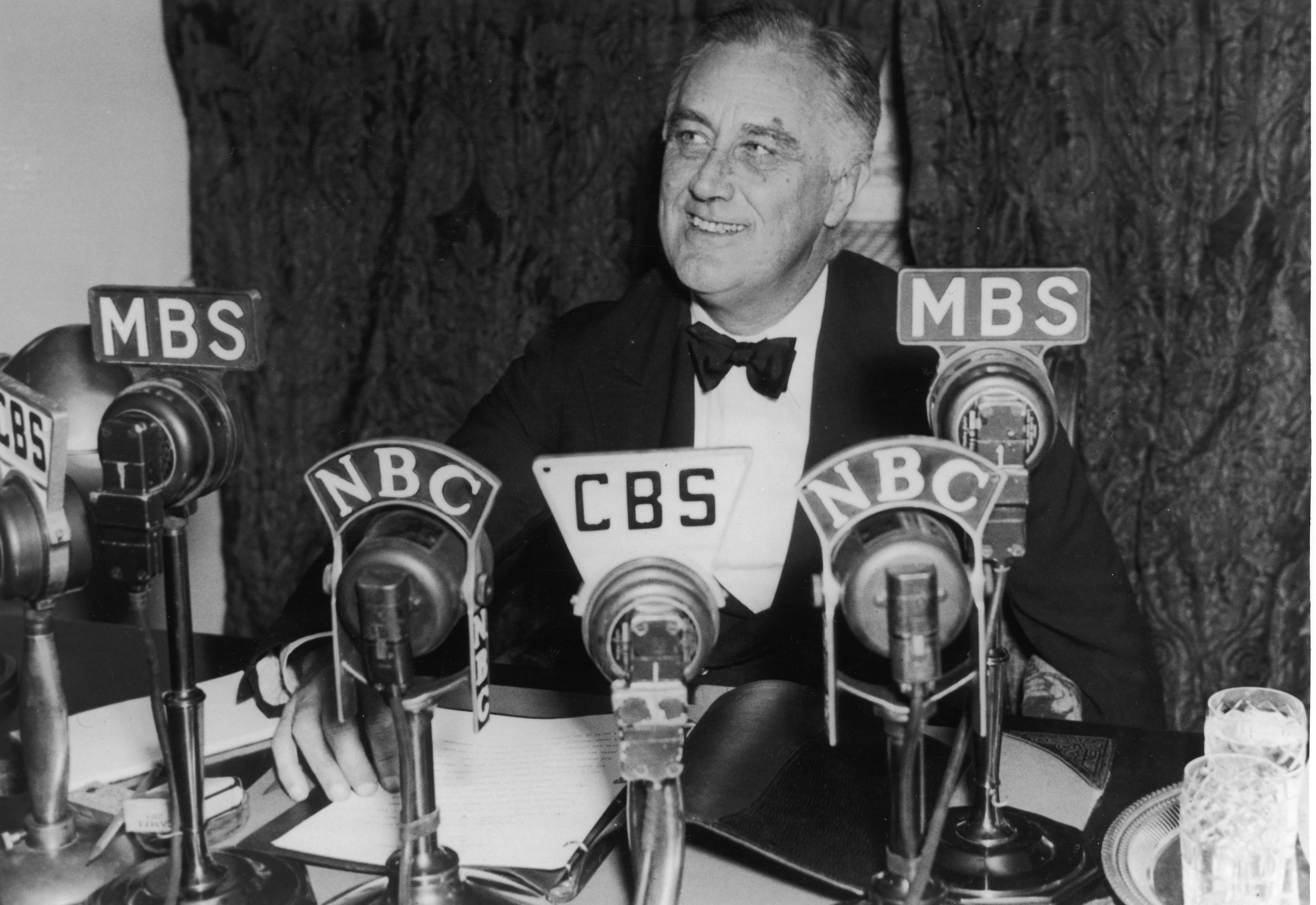 President Franklin D. Roosevelt seated in front of a number of television and radio station microphones in Washington D.C. asking communities to continue relief work, October 14, 1938. (Fotosearch—Getty Images)