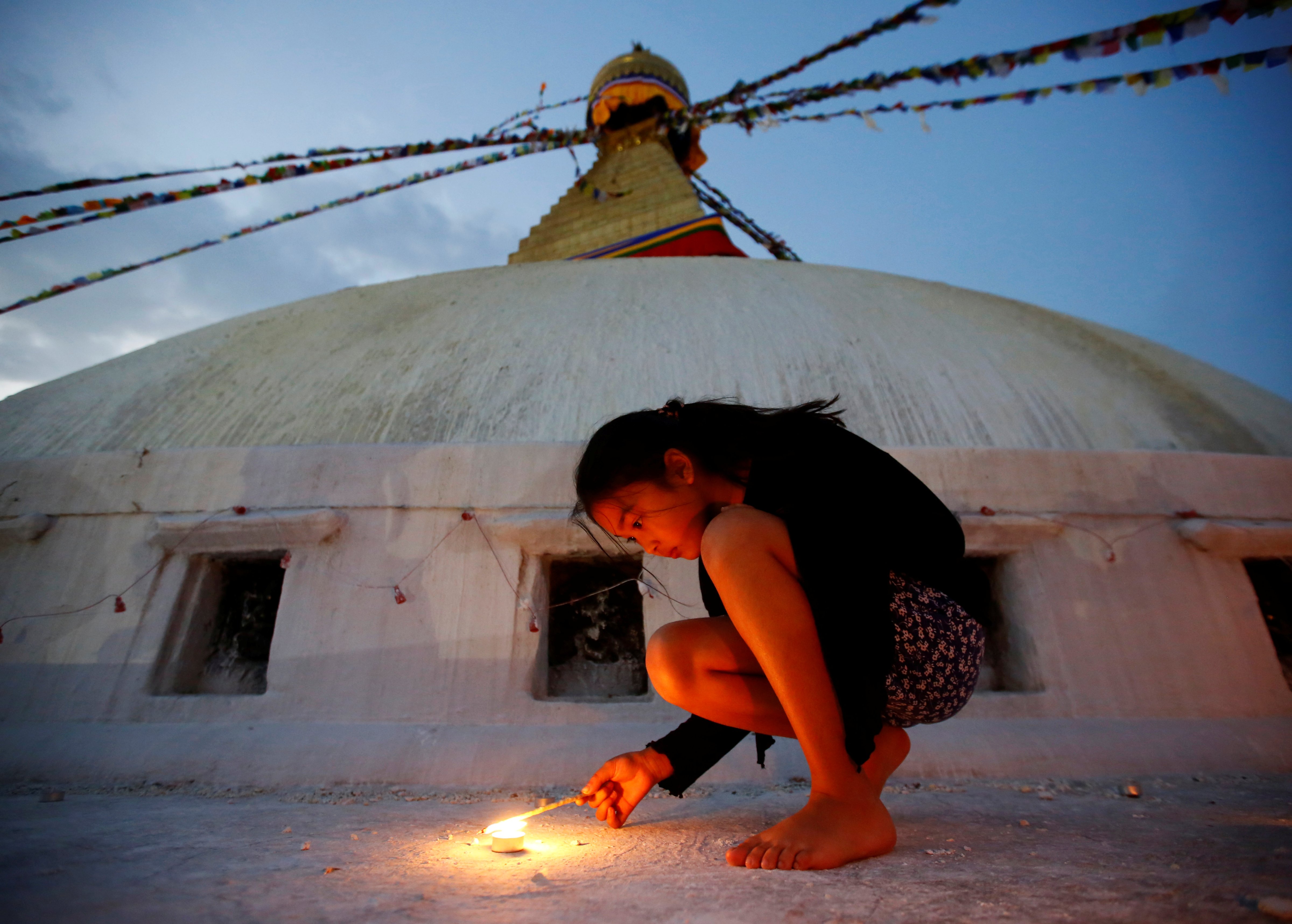A girl lights a candle as she marks the anniversary of 2015 Nepal earthquake, at Boudhanath stupa in Kathmandu on April 25, 2017 (Navesh Chitrakar—Reuters)