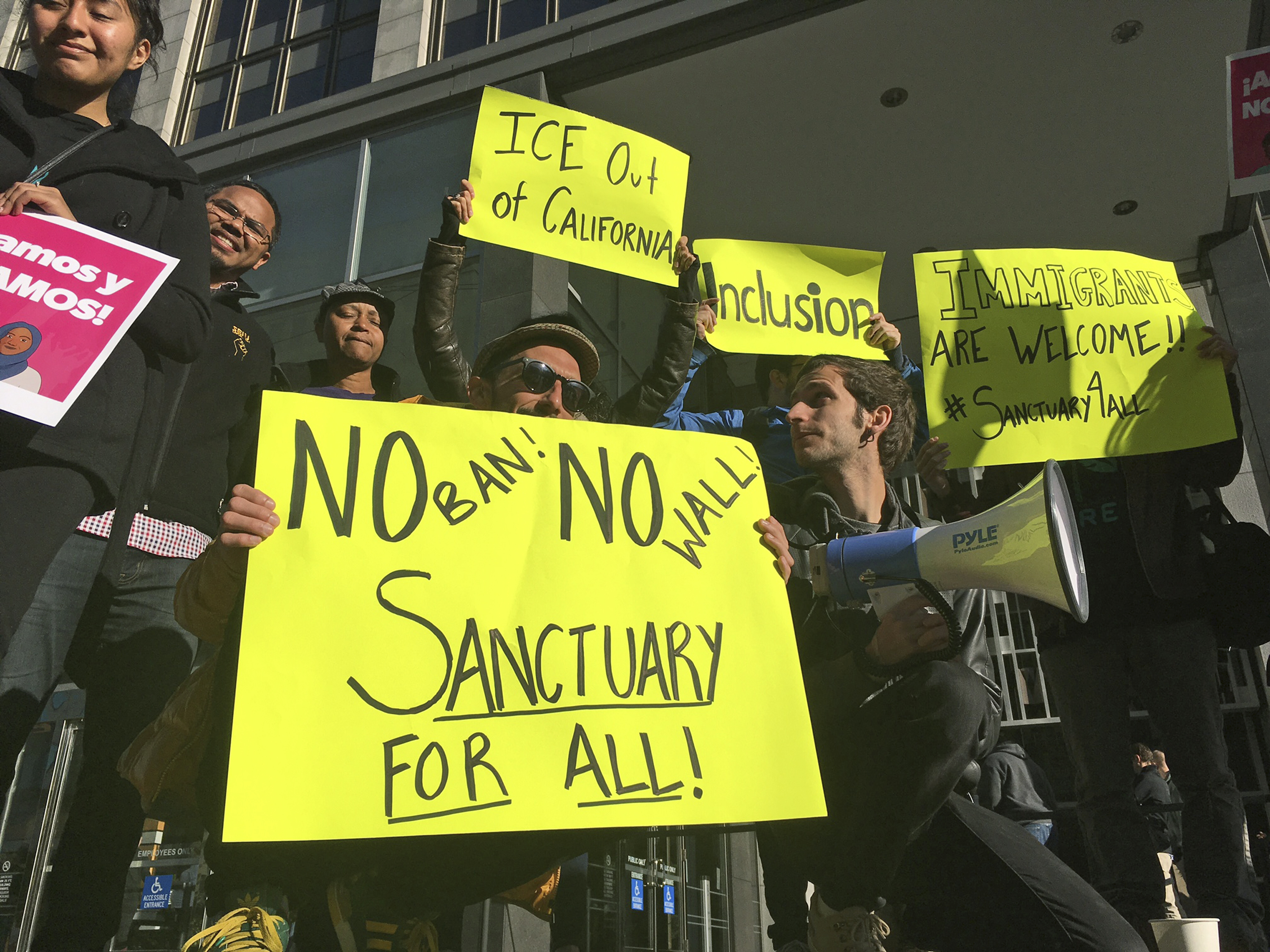 Protesters hold up signs outside a courthouse where a federal judge will hear arguments in the first lawsuit challenging President Donald Trump's executive order to withhold funding from communities that limit cooperation with immigration authorities on April 14, 2017, in San Francisco. (Haven Daley—AP)