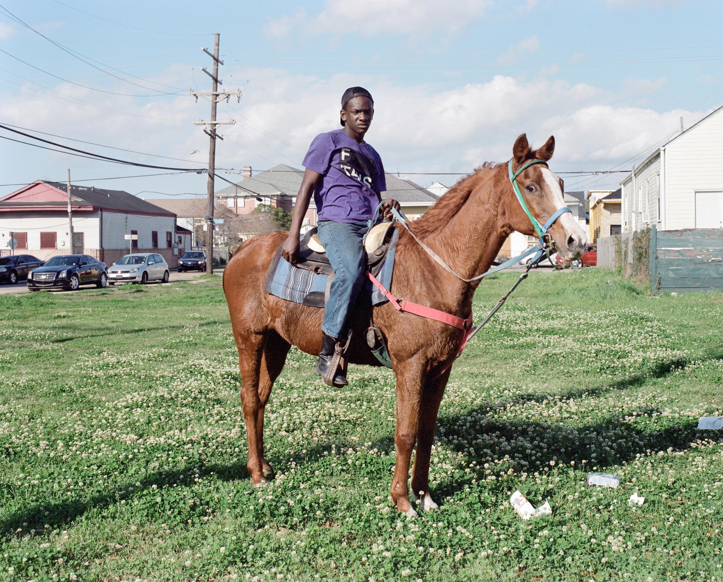 A boy poses on horseback at a Second Line in downtown New Orleans, Louisiana. 2016