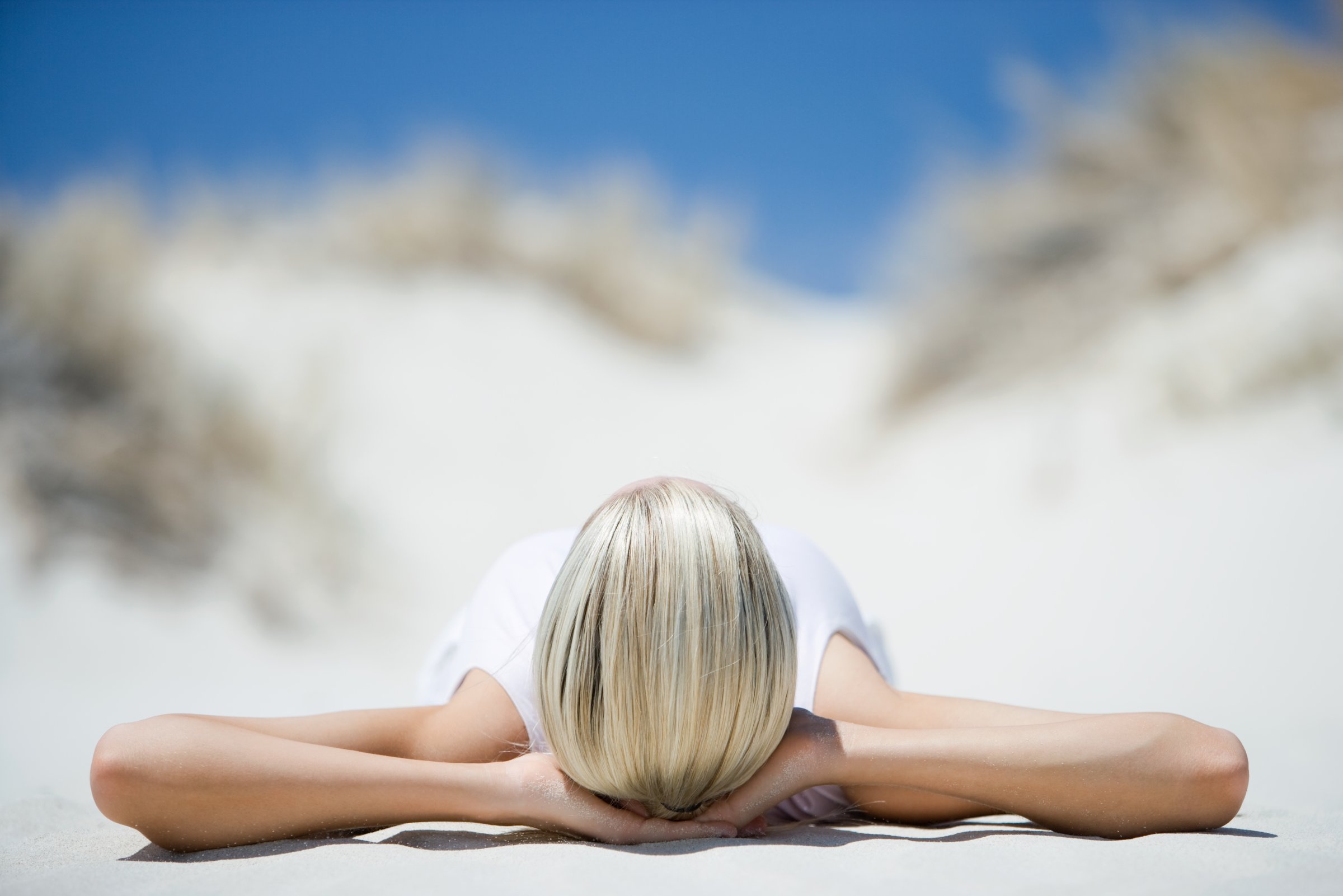 Young woman lying on beach, surface level, view of hands under head TIME health stock