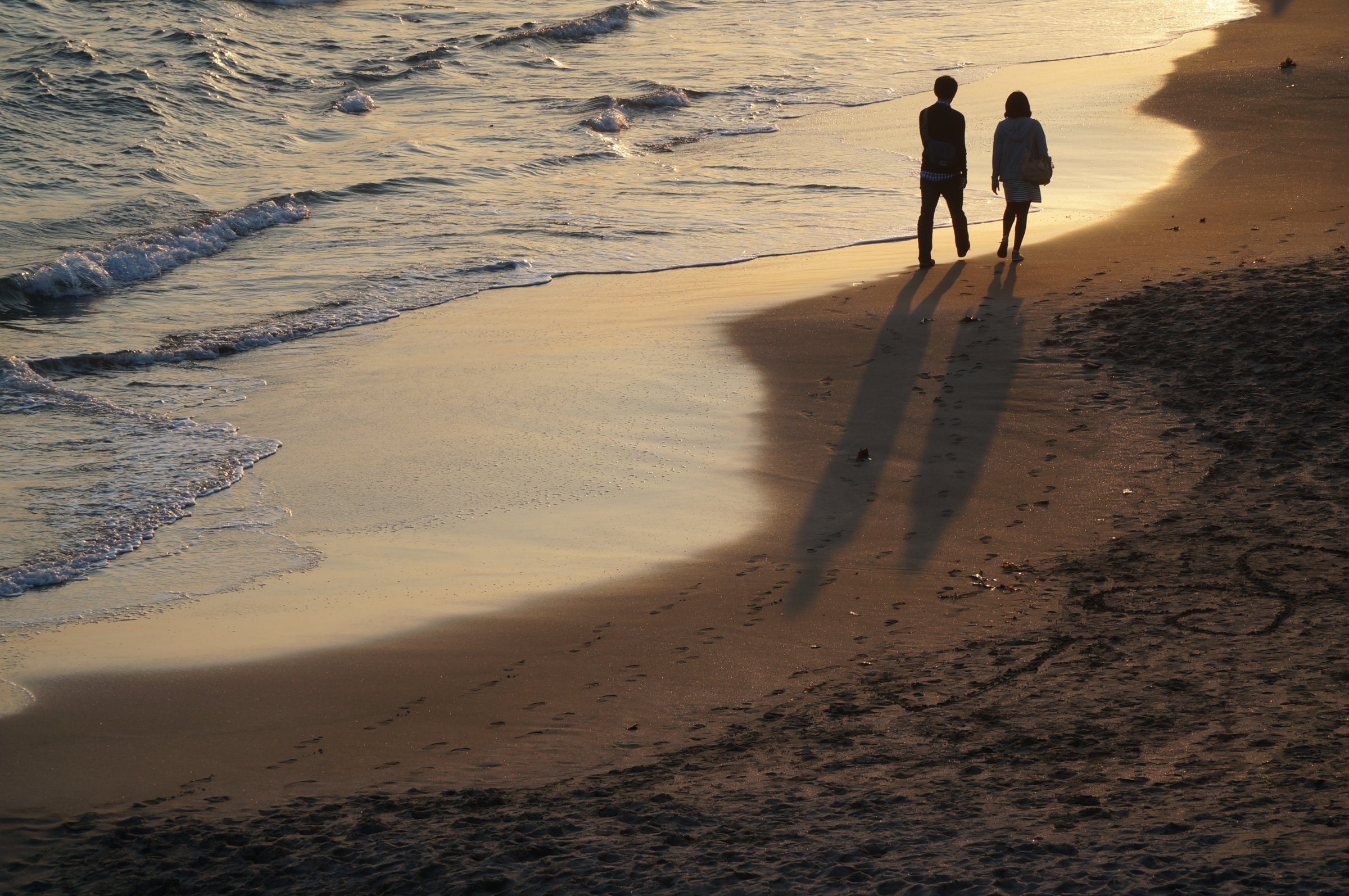 Lovers walking along golden colored seaside line in the sunset TIME health stock