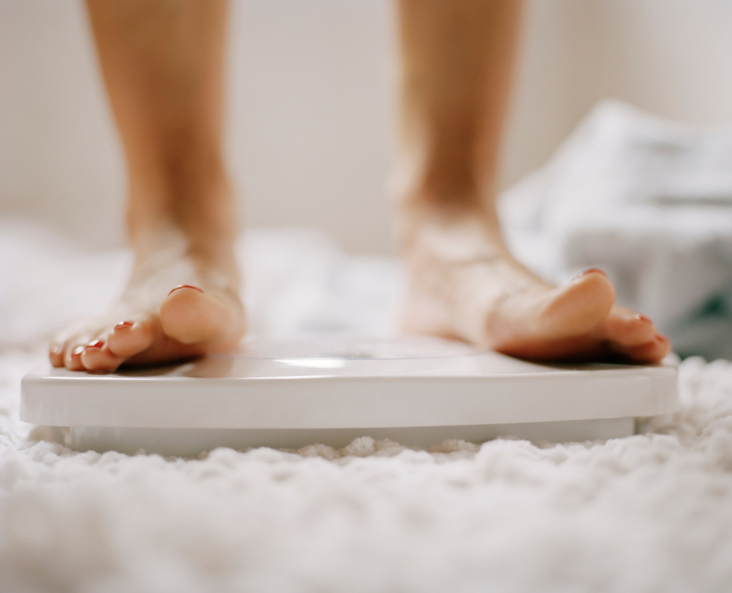 Close-up of woman's feet on scale TIME health stock