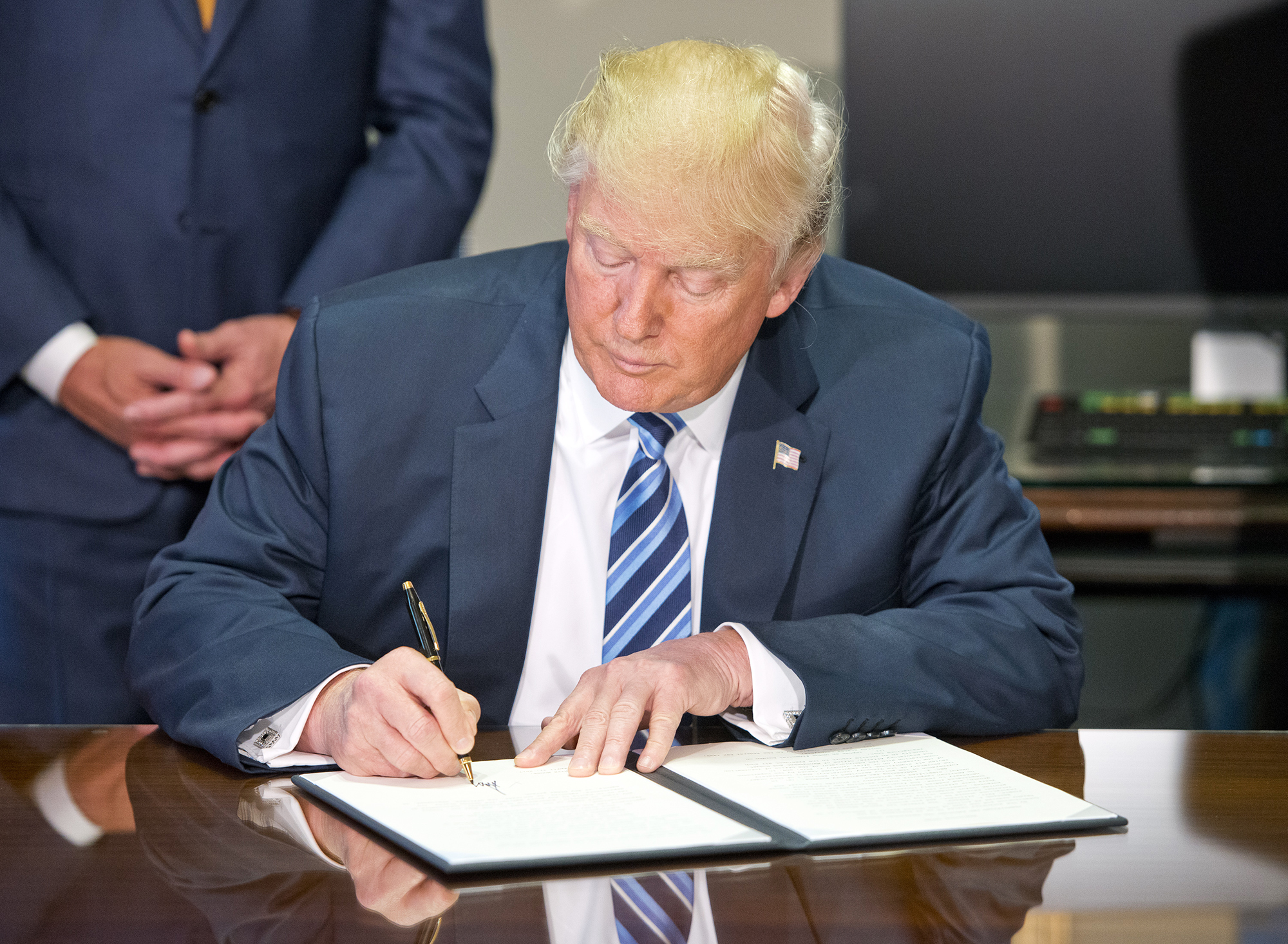 Donald Trump signs the first of three Executive Orders concerning financial services at the Department of the Treasury in Washington, D.C., on April 21, 2017. (Ron Sachs—AP)