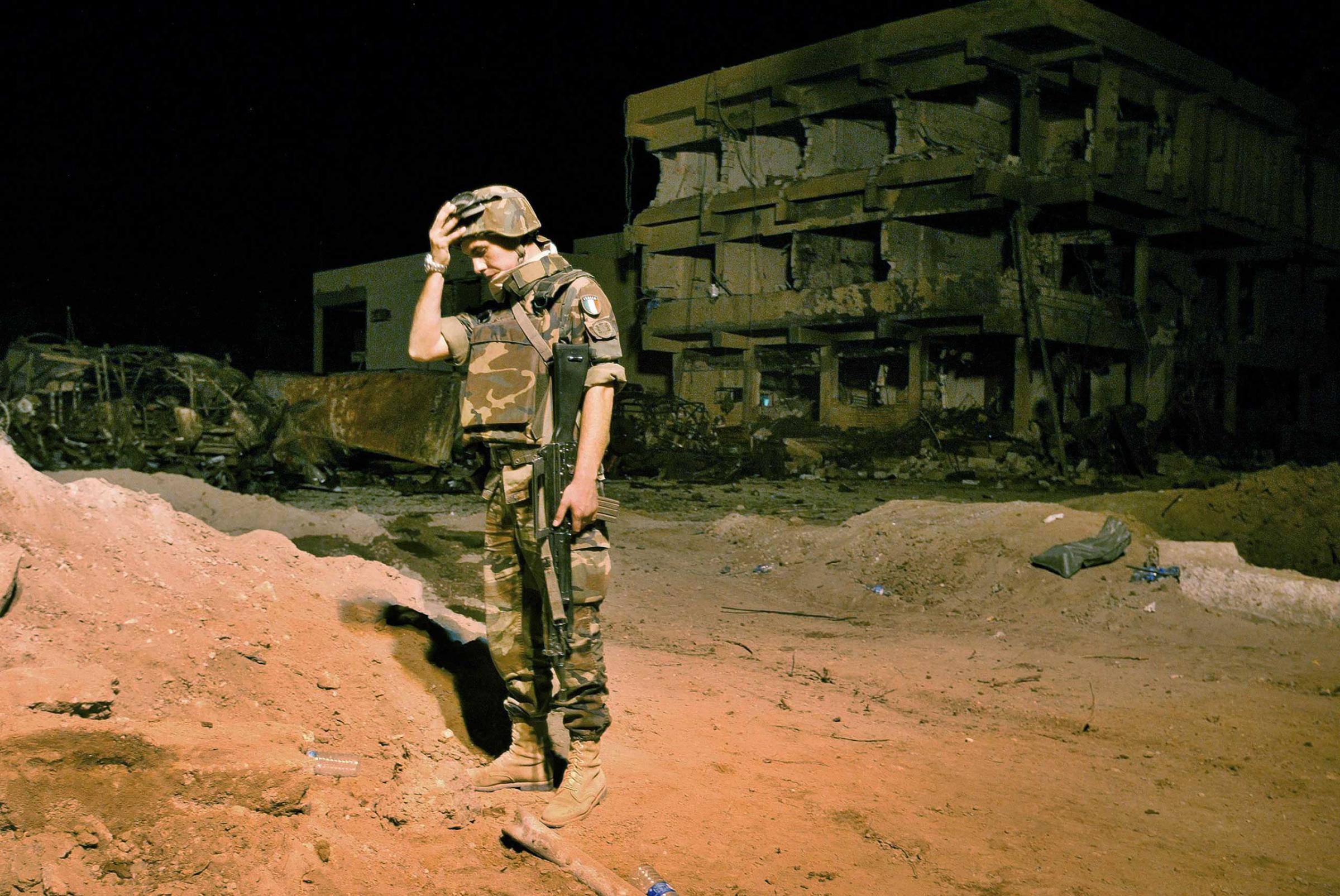 ONE-TIME USE FOR IWMF AWARDS -- An Italian Army soldier stands next to the barracks building which was destroyed by a car bomb at the headquarters of Italy's paramilitary police in the southern Iraqi city Nasiriyah, Nov. 12, 2003. Twenty-six people -- 19 of them Italian -- were killed in the suicide bombing. (AP Photo/Anja Niedringhaus)