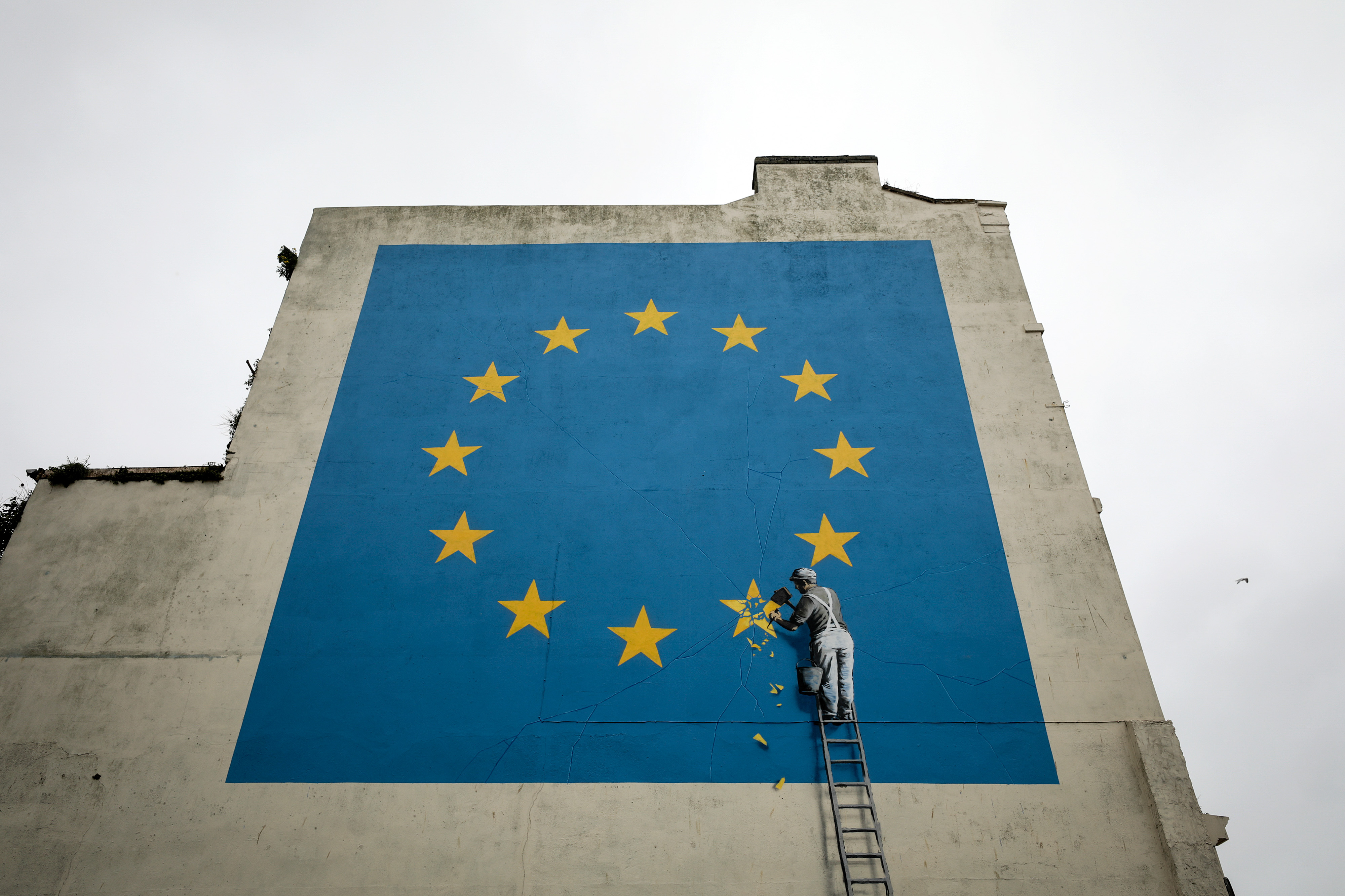 A mural depicting a European Union (EU) flag being chiseled by a workman sits on the side of a disused building near the ferry terminal in Dover, U.K., on Monday, May 8, 2017.