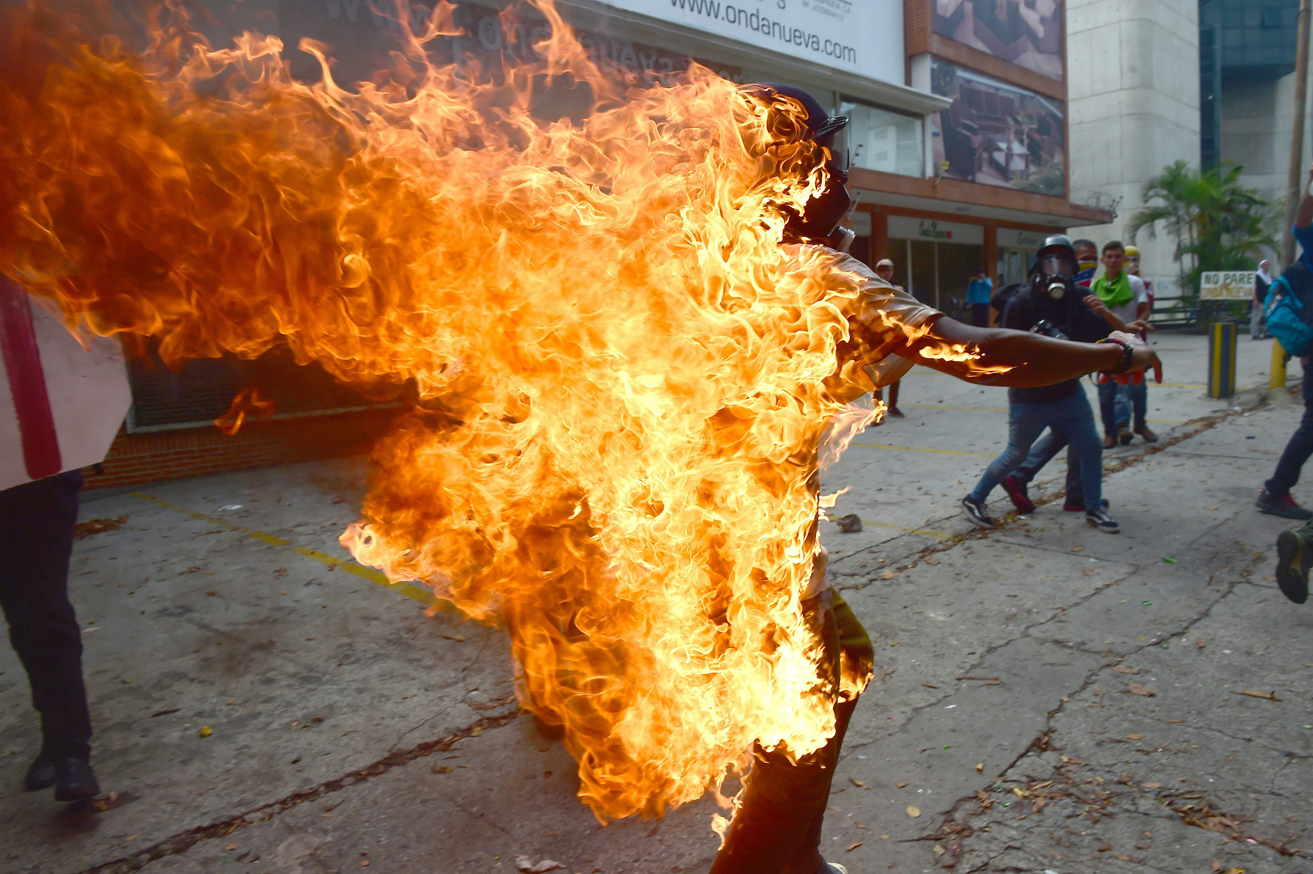 A man set ablaze during an anti-Maduro protest runs to put out the flames in Caracas on May 3, 2017.