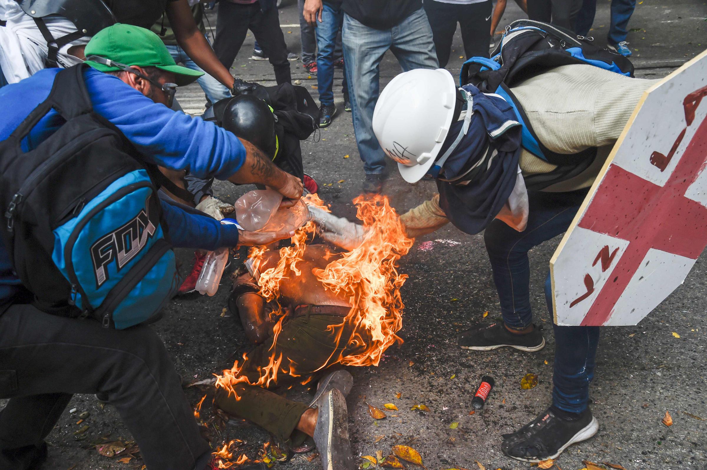 Men aid a demonstrator who caught fire during clashes in Caracas on May 3, 2017.