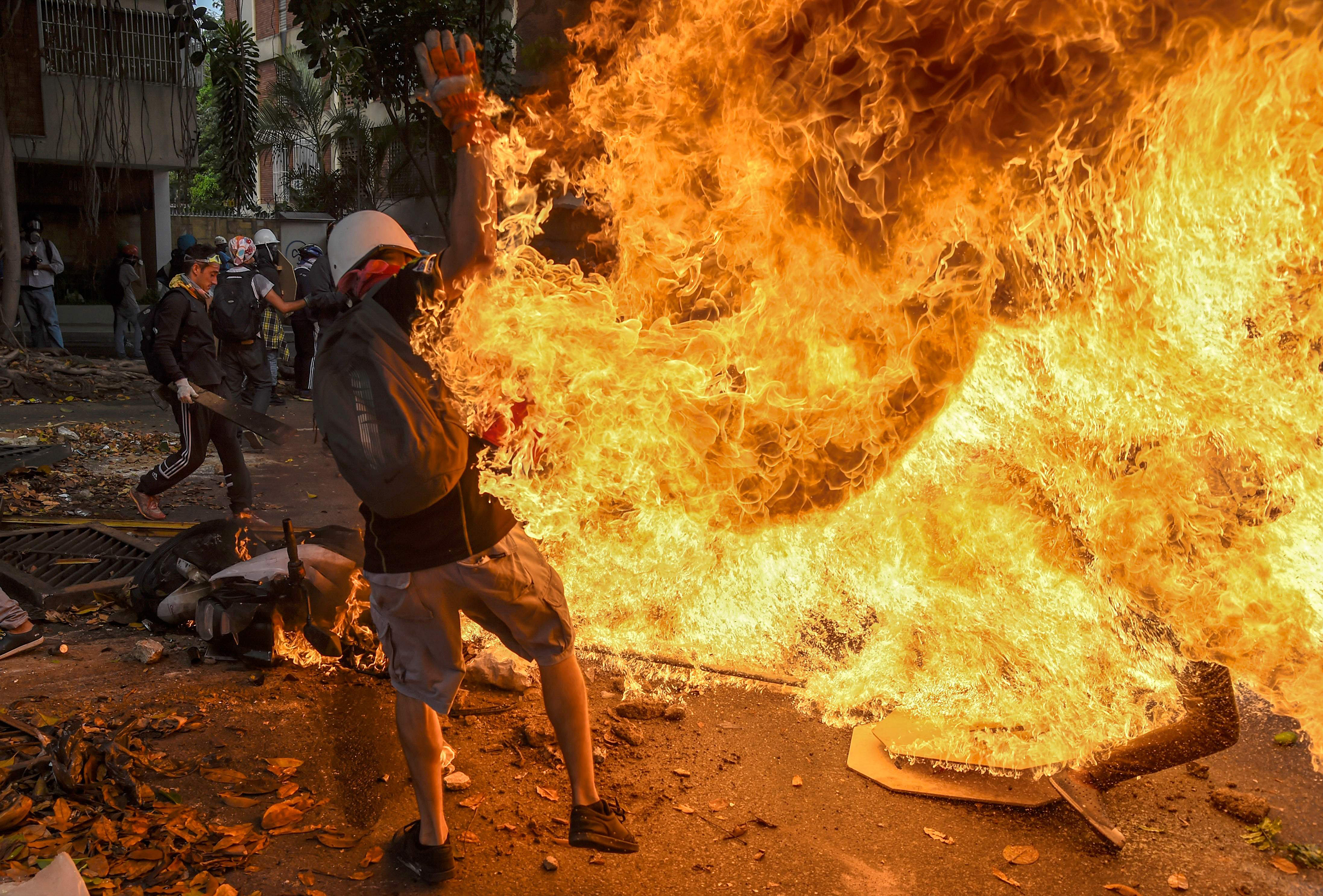 A man is engulfed in flames after the gas tank of a motorbike explodes in Caracas on May 3, 2017.