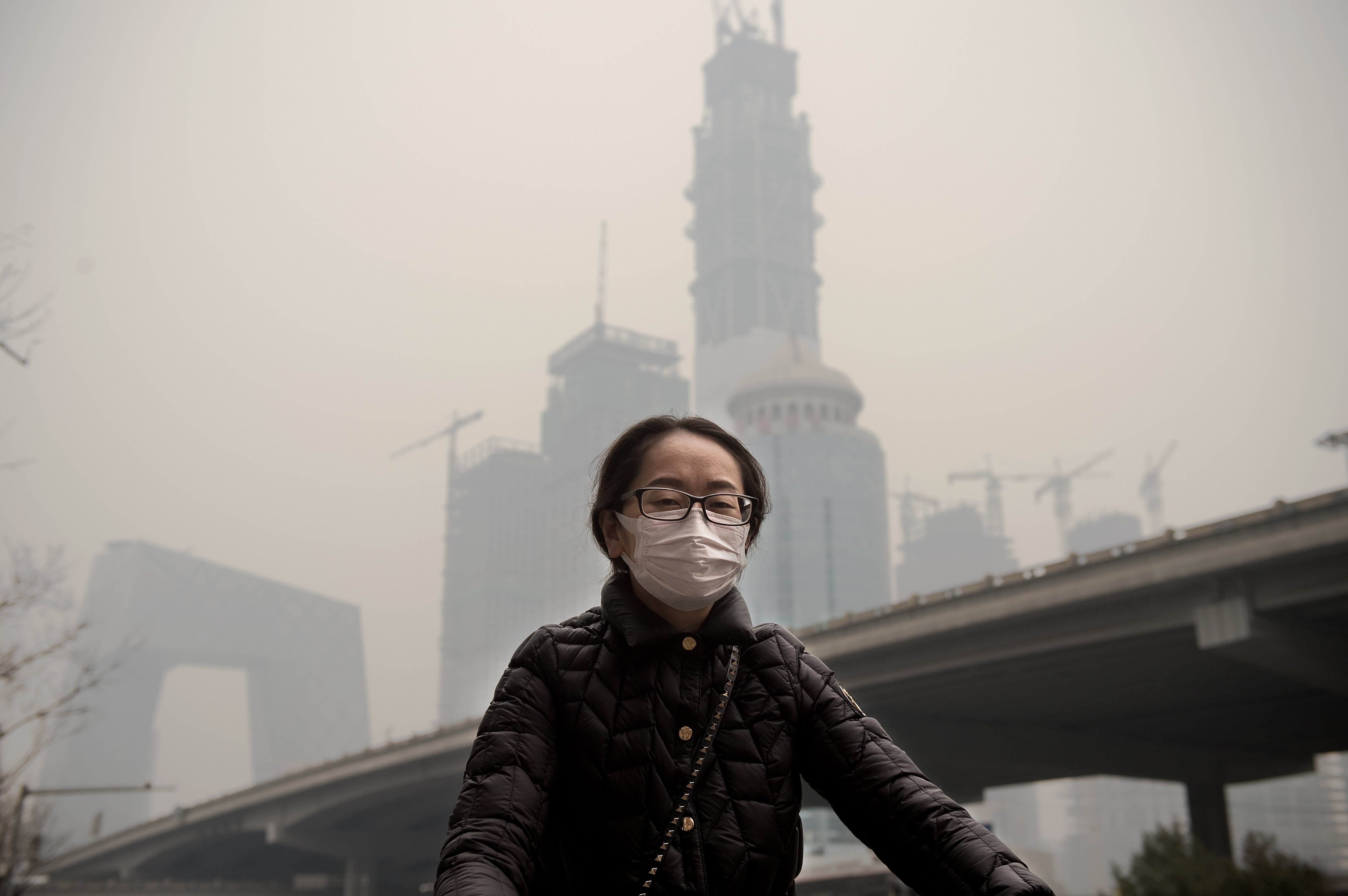 A woman wearing a protective pollution mask rides a bicycle in Beijing, China, on March 20, 2017. (Nicolas Asfouri&mdash;AFP/Getty Images)